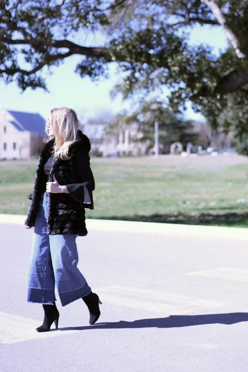 culotte jeans by olivia palmero from the nordstrom, chelsea 28 collaboration paired with tall black suede boots, a chicwish faux fur, hooded vest and a bell sleeve black top