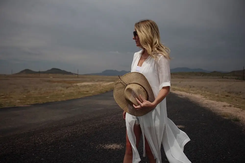 straw cowboy hat with distressed BLANK NYC denim shorts, maxi shirt from Asos and white tank in West Texas at Cibolo Creek Ranch