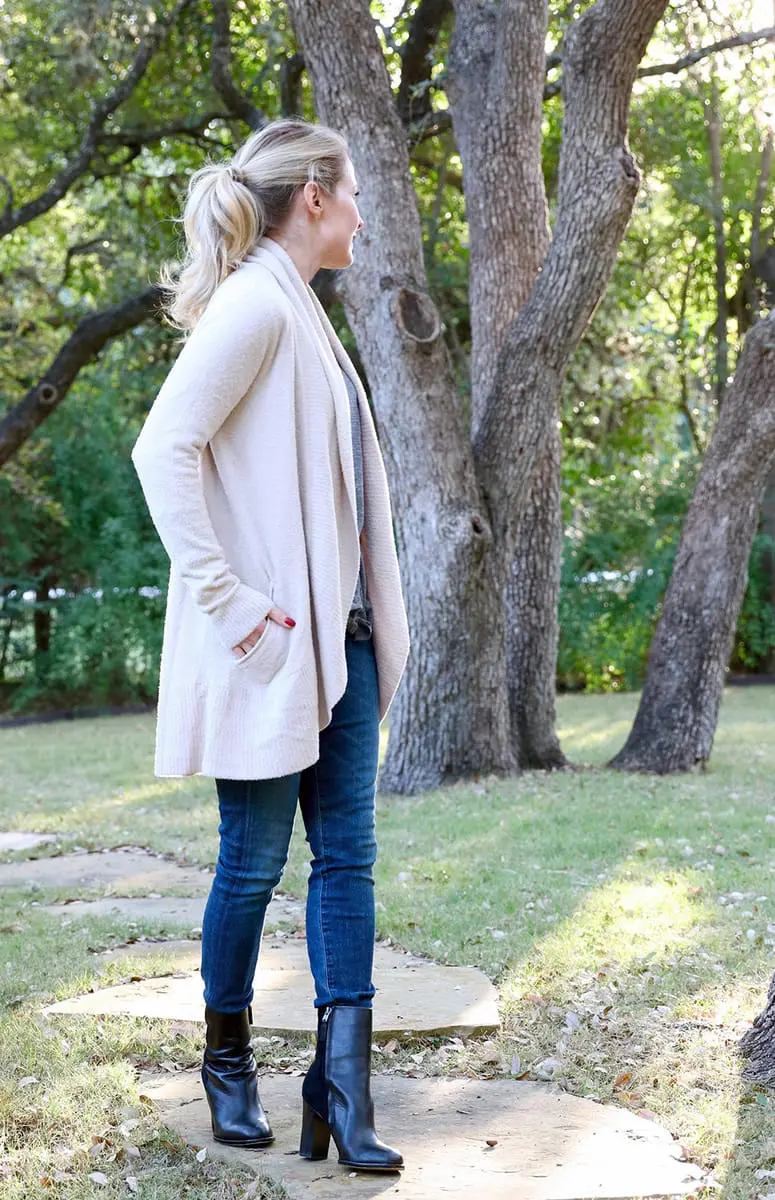 erin busbee of busbeestyle.com sitting down drinking coffee in dark wash skinny jeans, black booties, and a barefoot dreams fuzzy cardigan 