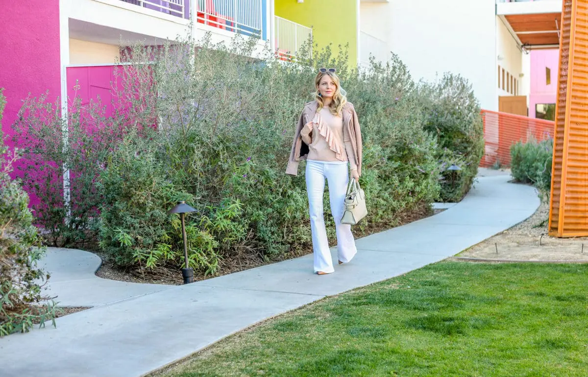 erin busbee from busbeestyle.com in palm springs for alt summit wearing wide leg white jeans, a ruffle peach sweater by topshop and an iro jacket called "Han" in taupe carrying a Henri Bendel handbag in sea salt white