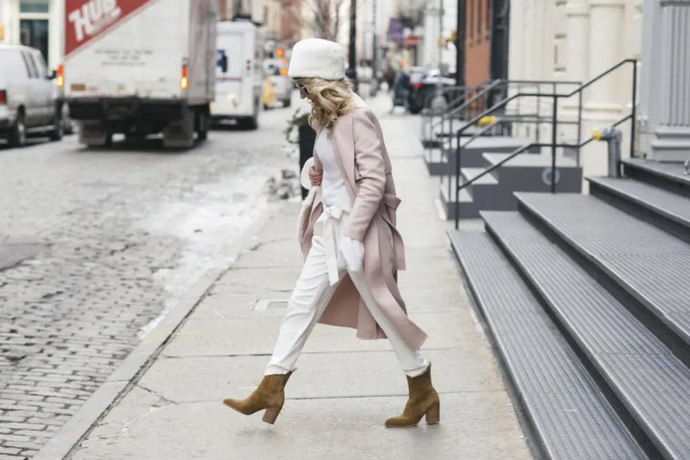 Erin Busbee at New York Fashion Week February 2017 wearing white parker new york jogging pants, with white cashmere turtleneck sweater, white faux fur pill box hat from New York & Company, faux fur wrap by Urbancode with Marc Fisher suede booties