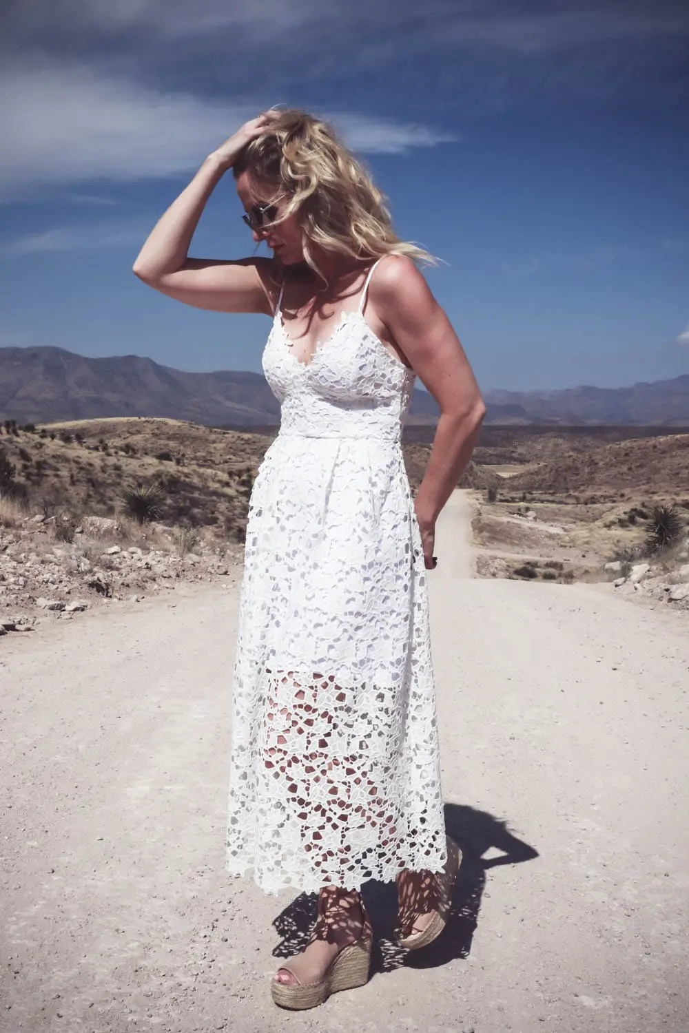 Fashion blogger and fashion youtuber, erin busbee of busbeestyle.com, wearing a white lace dress by ASTR, nude leather espadrille sandals by Marc Fisher (super comfortable) and the mirrored aviator sunglasses are by Quay Australia at Cibolo Creek Ranch in West Texas near Marfa
