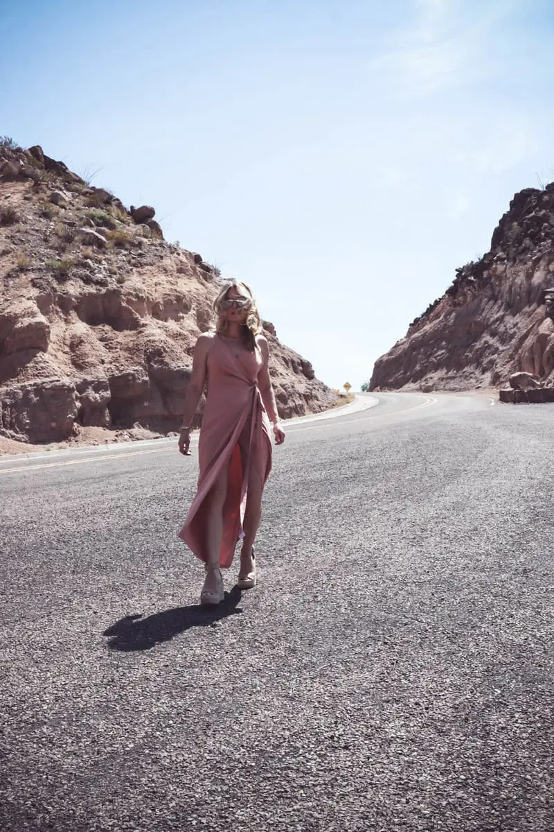 Wrap Dress by Wyldr from Asos and Revolve in blush nude color with Marc Fisher perforated ankle strap espadrilles wedges, on fashion blogger and fashion youtuber erin busbee of busbestyle, san antonio, texas, shot near Big Bend National Park in West Texas along the Rio Grande, walking on a rocky road in the desert 