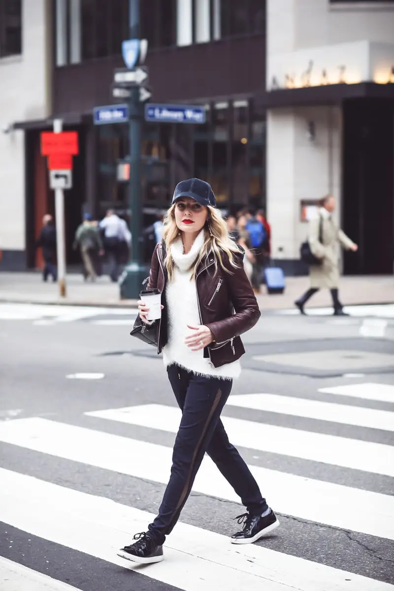 Gym to street pants, perfect for creating the athleisure look on fashion blogger over 40, Erin Busbee of Busbee Style paired with fuzzy white turtleneck sweater, doma leather hooded leather jacket and Henri Bendel leather jetsetter backpack with patent leather sneakers by Kenneth Cole