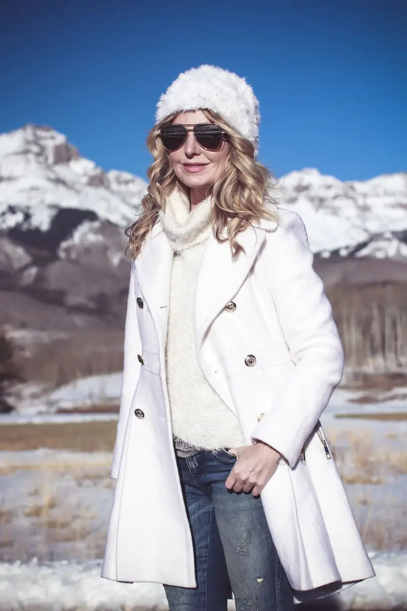 White coat, winter white coat, double breasted by Guess in boucle, paired with Sorel Conquest booties, Amo twist skinny jeans, a white fuzzy hat and a fuzzy white sweater, on Fashion Blogger over 40, Erin Busbee of Busbee Style, BusbeeStyle.com in telluride, Colorado in the snowy mountains