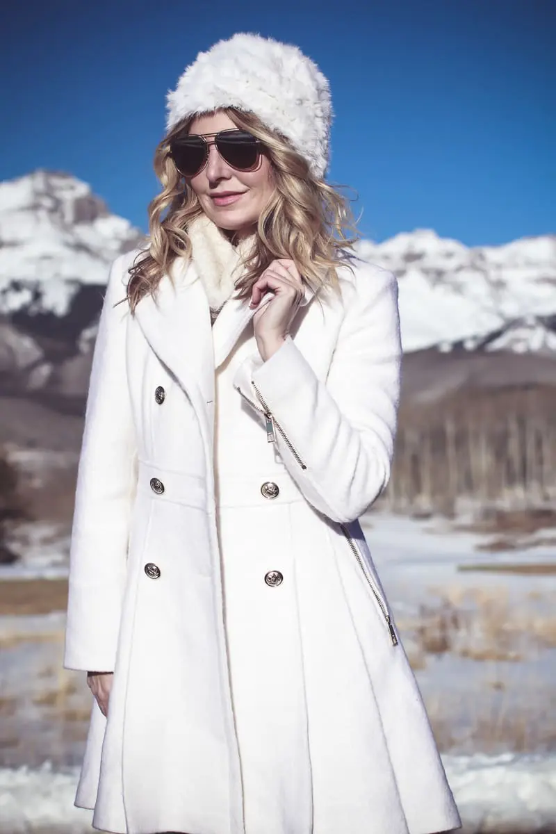 White coat, winter white coat, double breasted by Guess in boucle, paired with Sorel Conquest booties, Amo twist skinny jeans, a white fuzzy hat and a fuzzy white sweater, on Fashion Blogger over 40, Erin Busbee of Busbee Style, BusbeeStyle.com