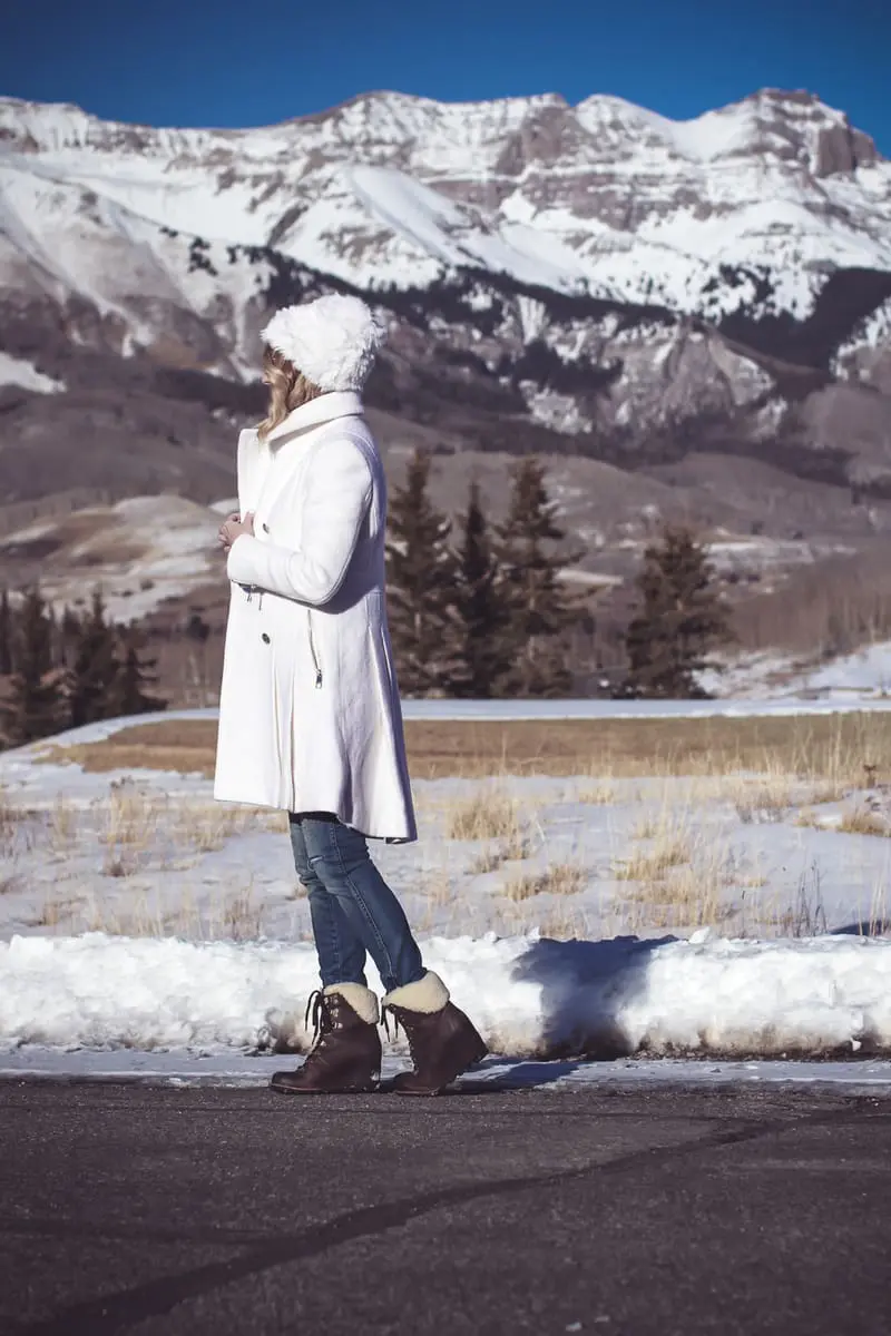 White coat, winter white coat, double breasted by Guess in boucle, paired with Sorel Conquest booties, Amo twist skinny jeans, a white fuzzy hat and a fuzzy white sweater, on Fashion Blogger over 40, Erin Busbee of Busbee Style, BusbeeStyle.com