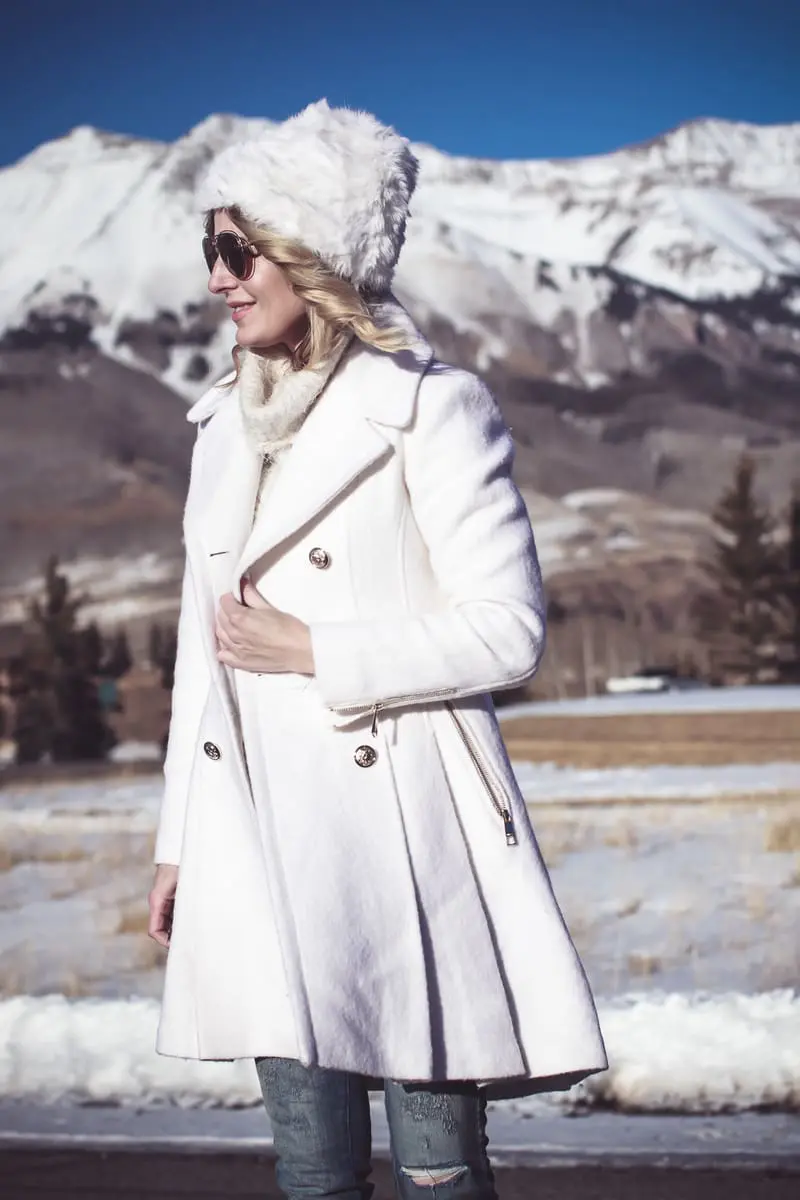 White coat, winter white coat, double breasted by Guess in boucle, paired with Sorel Conquest booties, Amo twist skinny jeans, a white fuzzy hat and a fuzzy white sweater, on Fashion Blogger over 40, Erin Busbee of Busbee Style, BusbeeStyle.com