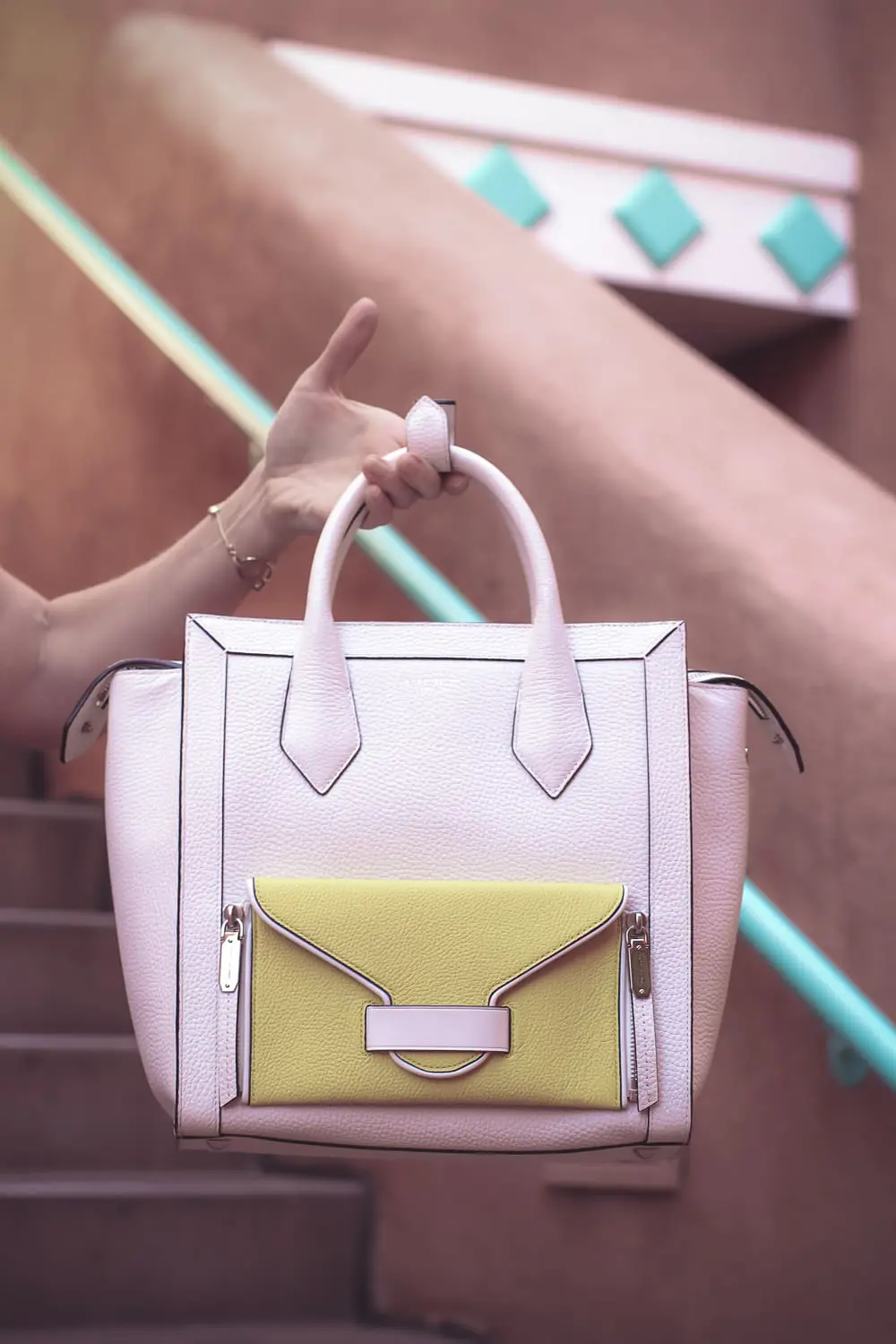 chic and sophisticated backpacks for grown ups by Henri Bendel, featuring blonde woman carrying a white Rivington convertible tote and backpack wearing all black with dainty gold and green jewelry