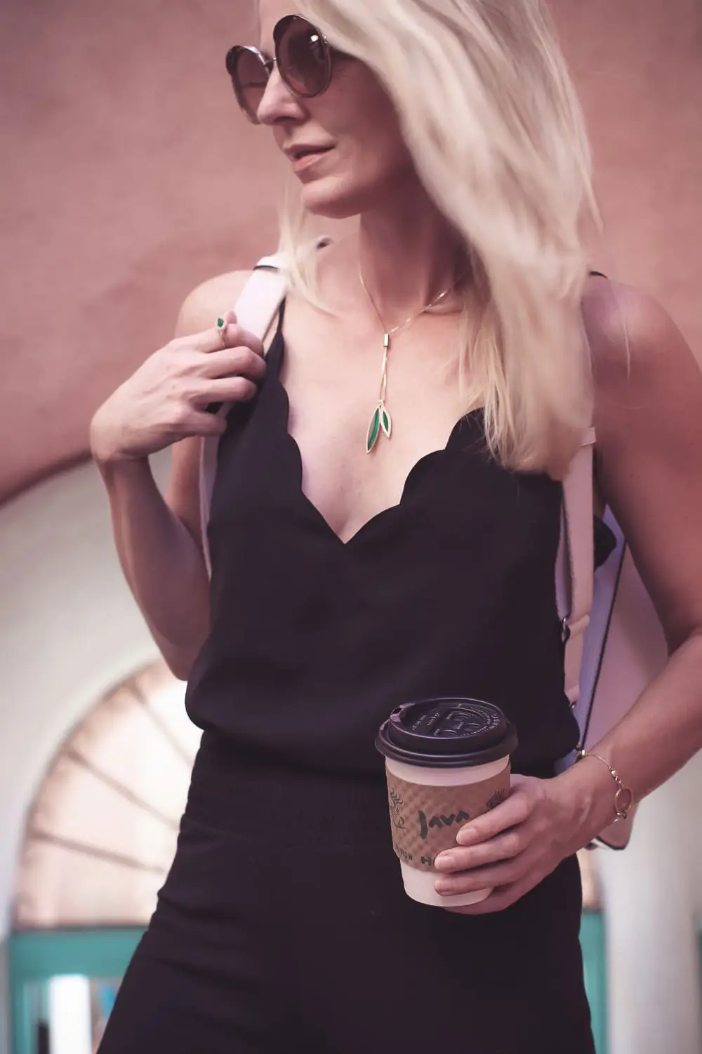 chic and sophisticated backpacks for grown ups by Henri Bendel, featuring blonde woman carrying a white Rivington convertible tote and backpack wearing all black with dainty gold and green jewelry