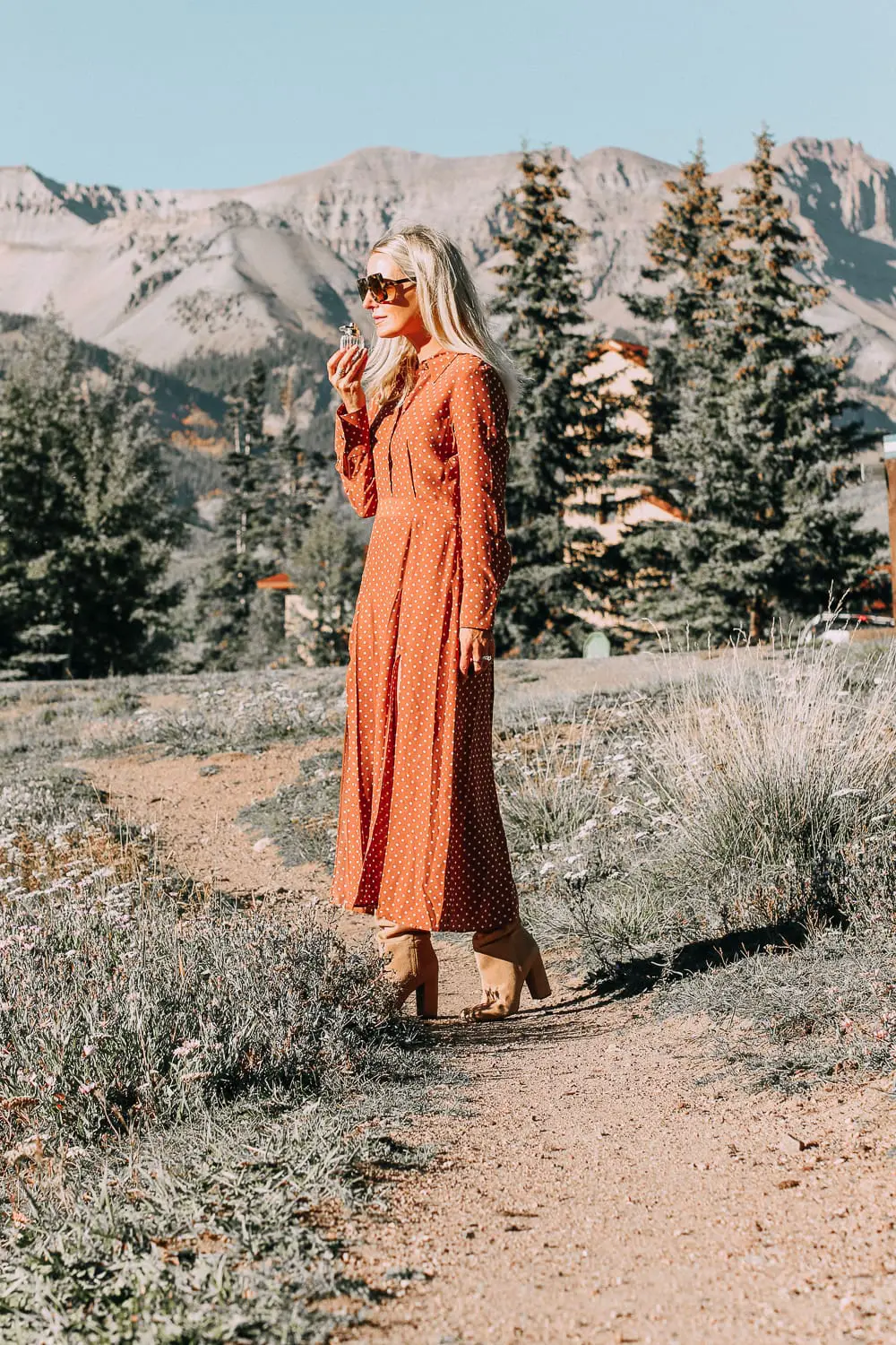 Signature Scent, finding your fragrance featuring Cartier Carat Eau de Parfum carried by blonde woman in the mountains in the fall season