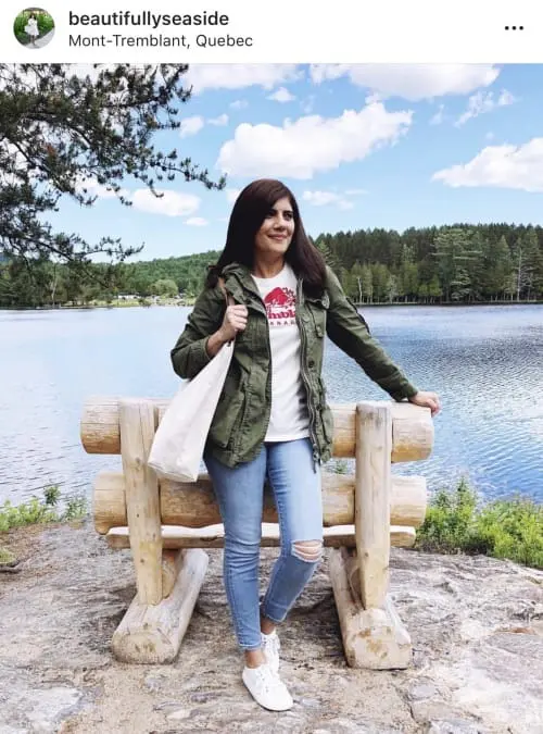 40+ fashion blogger beautifullyseaside wearing skinny jeans, white tennis shoes, logo t-shirt and green cargo jacket while carrying a canvas tote