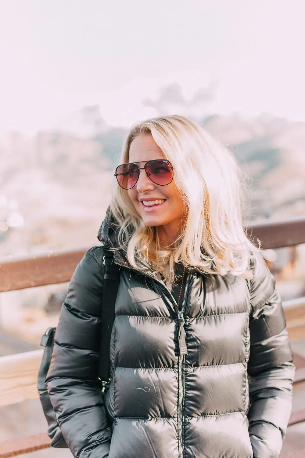 best puffer coats for women by Parajumpers from Bloomingdales in black, long puffer coat paired with dark jeans, black Ugg wedge booties on blonde woman