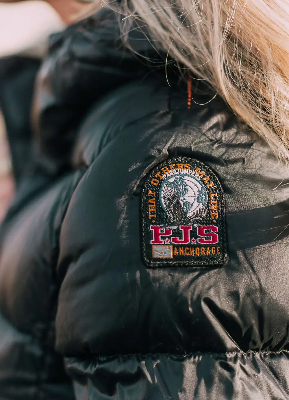 best puffer coats for women by Parajumpers from Bloomingdales in black, long puffer coat paired with dark jeans, black Ugg wedge booties on blonde woman