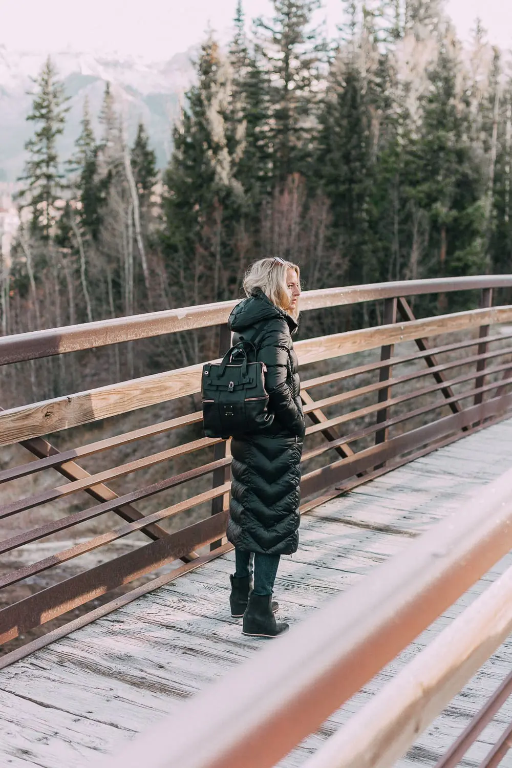 best puffer coats for women by Parajumpers from Bloomingdales in black, long puffer coat paired with dark jeans, black Ugg wedge booties on blonde woman
