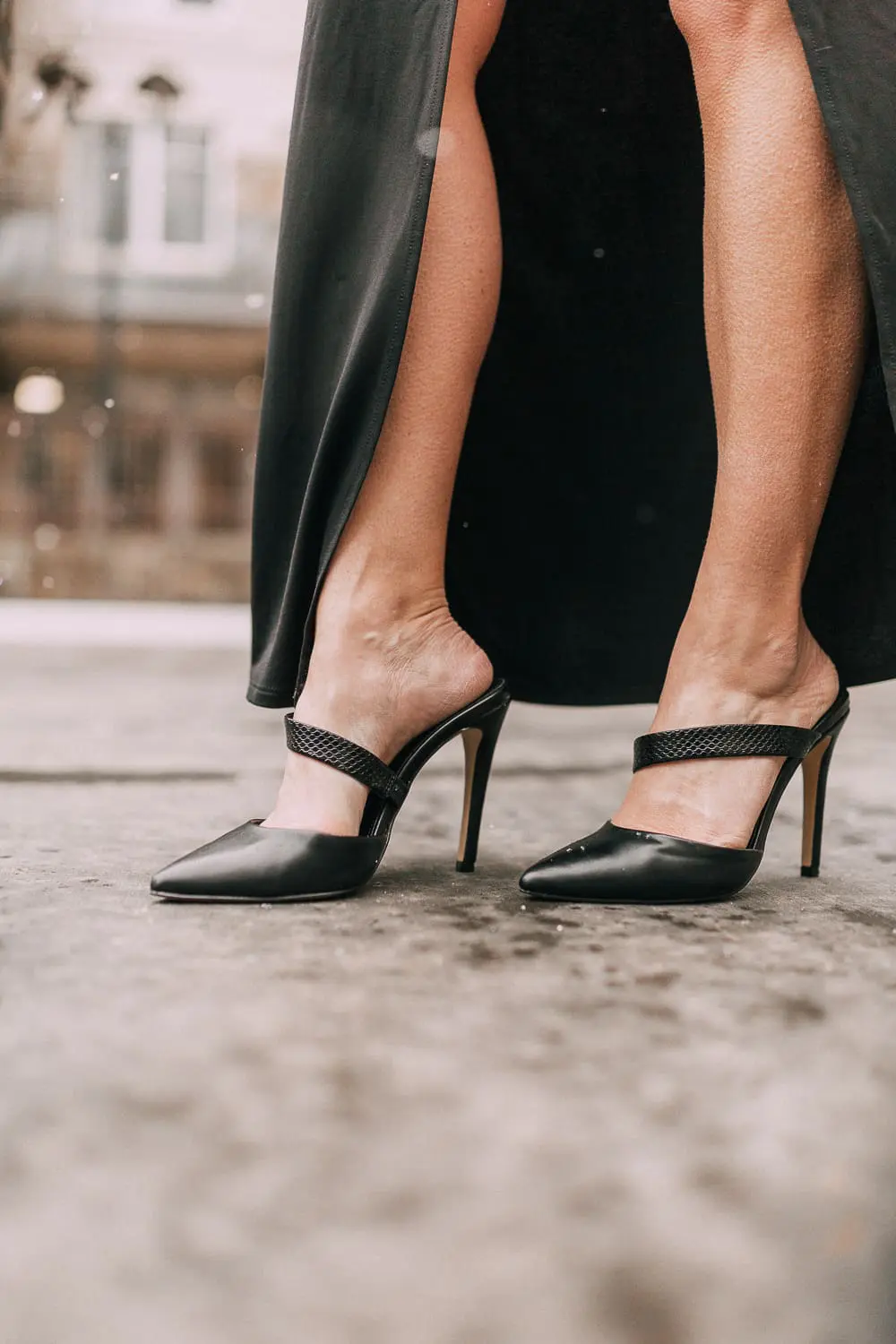 Unexpected holiday party outfits featuring a long black maxi dress with high slit to show off legs and a knot under the bust on blonde fashion blogger in telluride, colorado in the snow