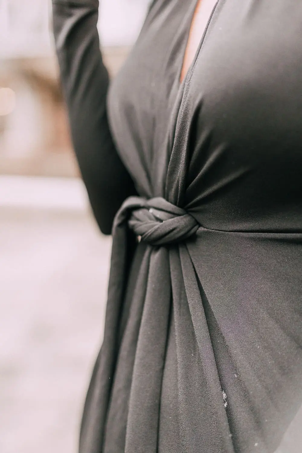 Unexpected holiday party outfits featuring a long black maxi dress with high slit to show off legs and a knot under the bust on blonde fashion blogger in telluride, colorado in the snow