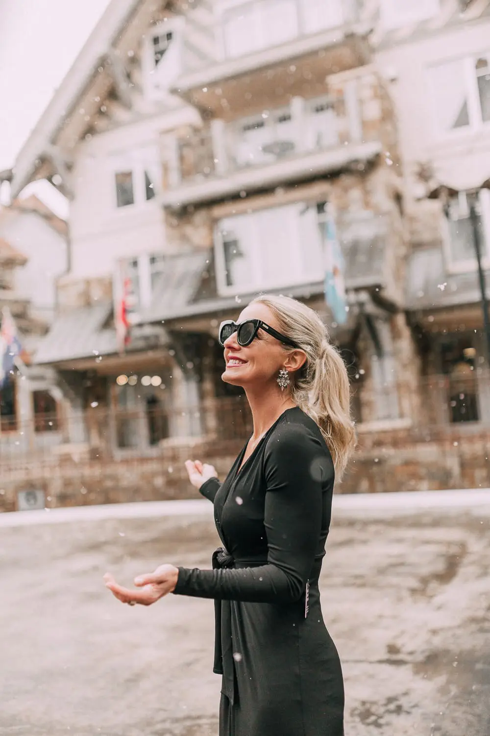 Unexpected holiday party outfits featuring a long black maxi dress with high slit to show off legs and a knot under the bust on blonde fashion blogger in telluride, colorado in the snow