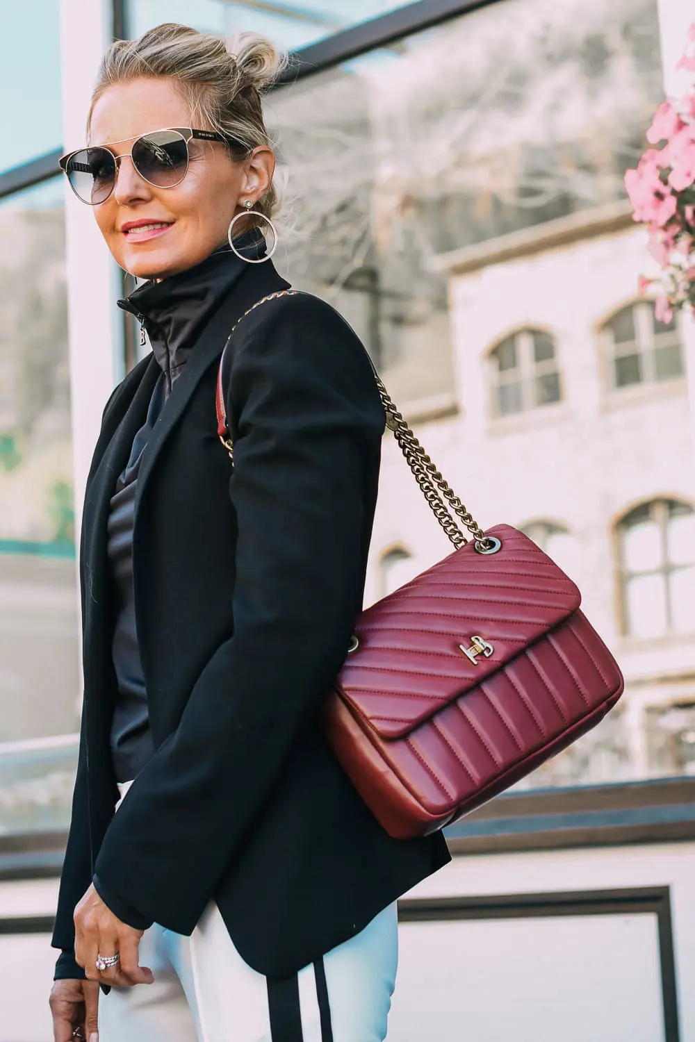 Henri Bendel quilted crossbody bag in burgundy with gold chain link detail paired with Pam & Gela striped pants, Bogner turtleneck and black blazer