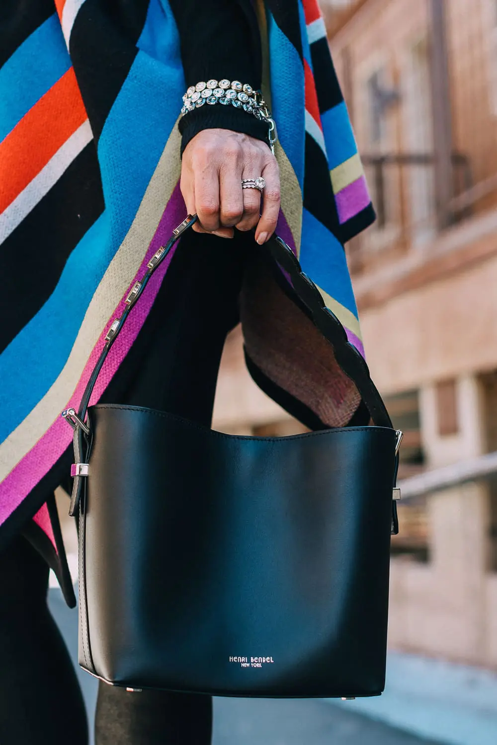 striped poncho, spanx leggings, vince camuto booties and henri bendel black bucket bag with gold hardware