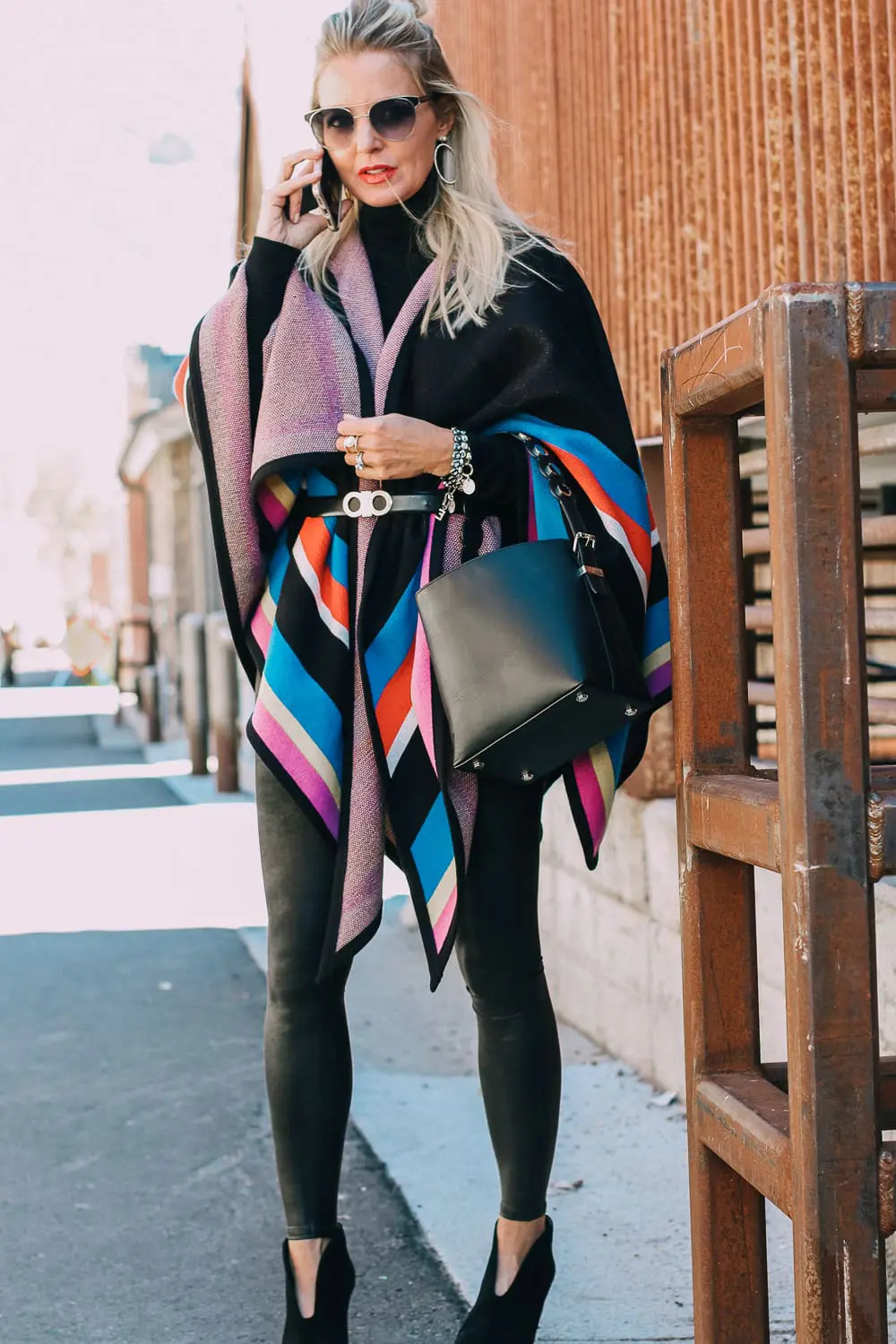 striped poncho, spanx leggings, vince camuto booties and henri bendel black bucket bag with gold hardware
