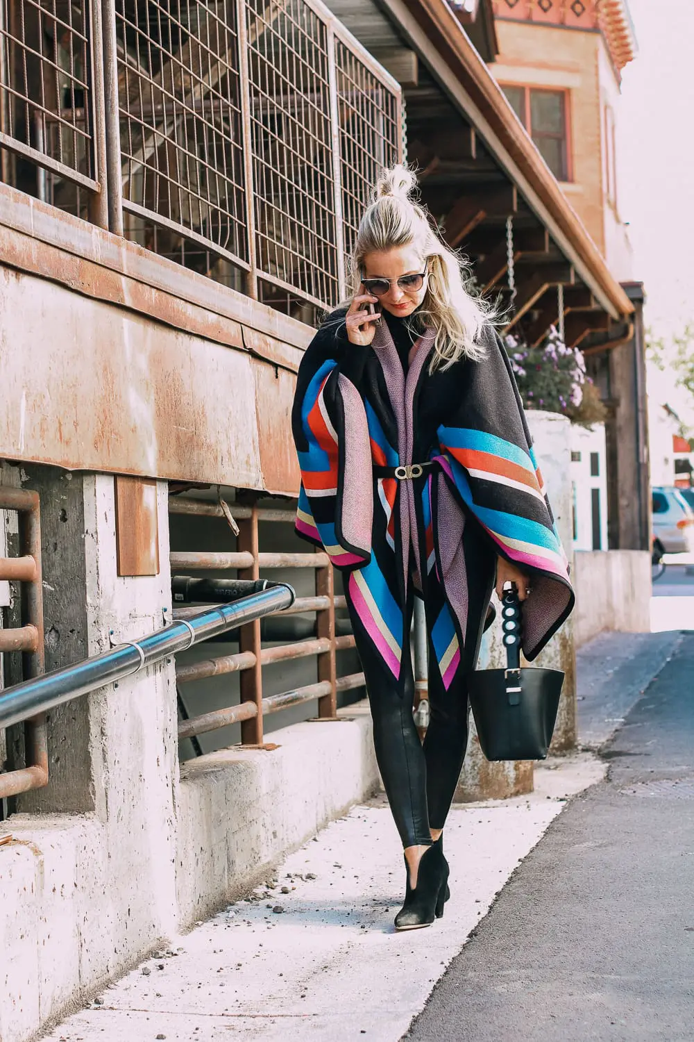 striped poncho, spanx leggings, vince camuto booties and henri bendel black bucket bag with gold hardware
