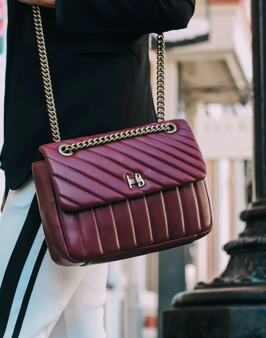 Henri Bendel quilted crossbody bag in burgundy with gold chain link detail paired with Pam & Gela striped pants, Bogner turtleneck and black blazer