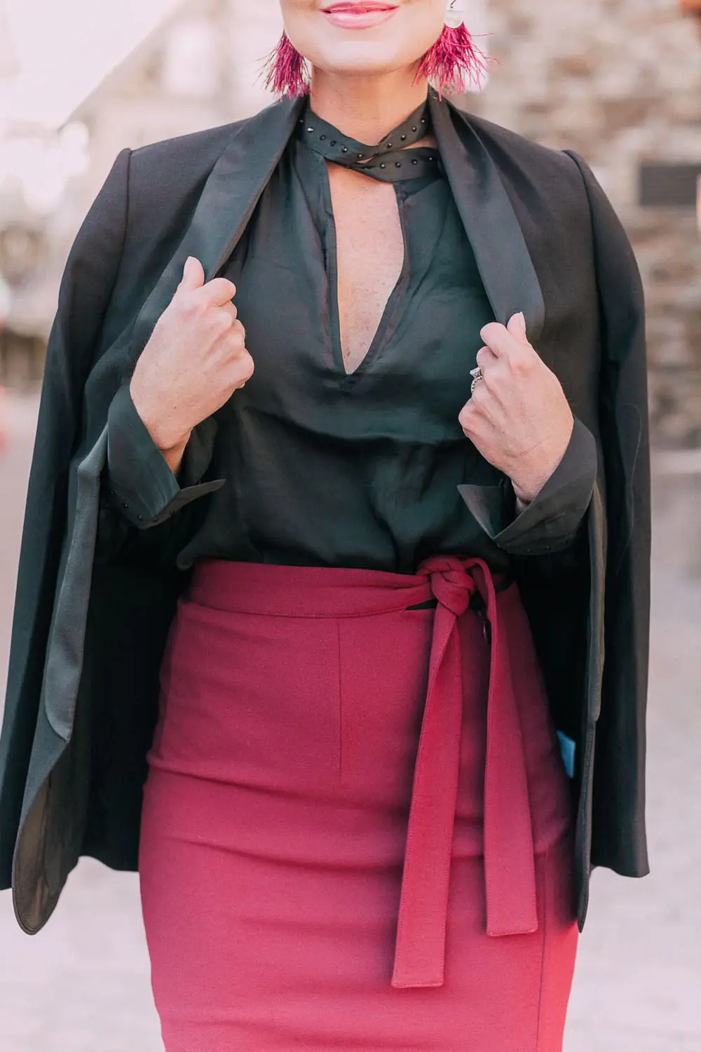 What to wear to a holiday party when it's cold outside, featuring a burgundy pencil skirt, black silky tie neck blouse, black diamond print tights, crystal studded ankle booties, and a black tuxedo blazer from Express 