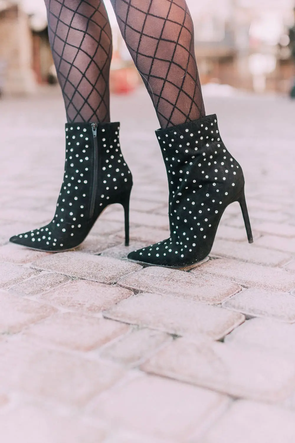 What to wear to a holiday party when it's cold outside, featuring a burgundy pencil skirt, black silky tie neck blouse, black diamond print tights, crystal studded ankle booties, and a black tuxedo blazer from Express 