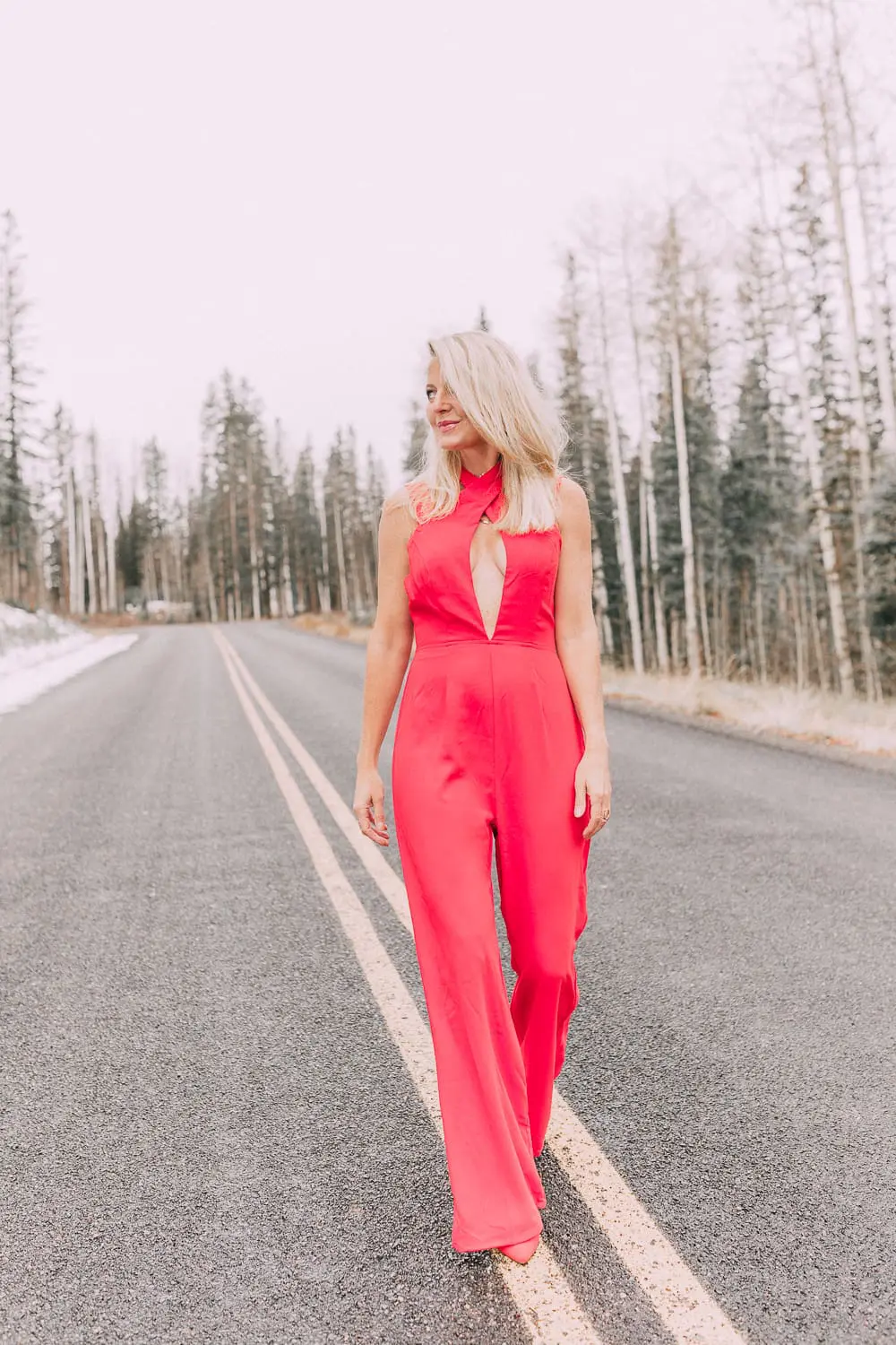 Fashion blogger Erin Busbee of BusbeeStyle.com wearing a bright red jumpsuit with keyhole cutout by By The Way. with matching red booties walking in Telluride, Colorado