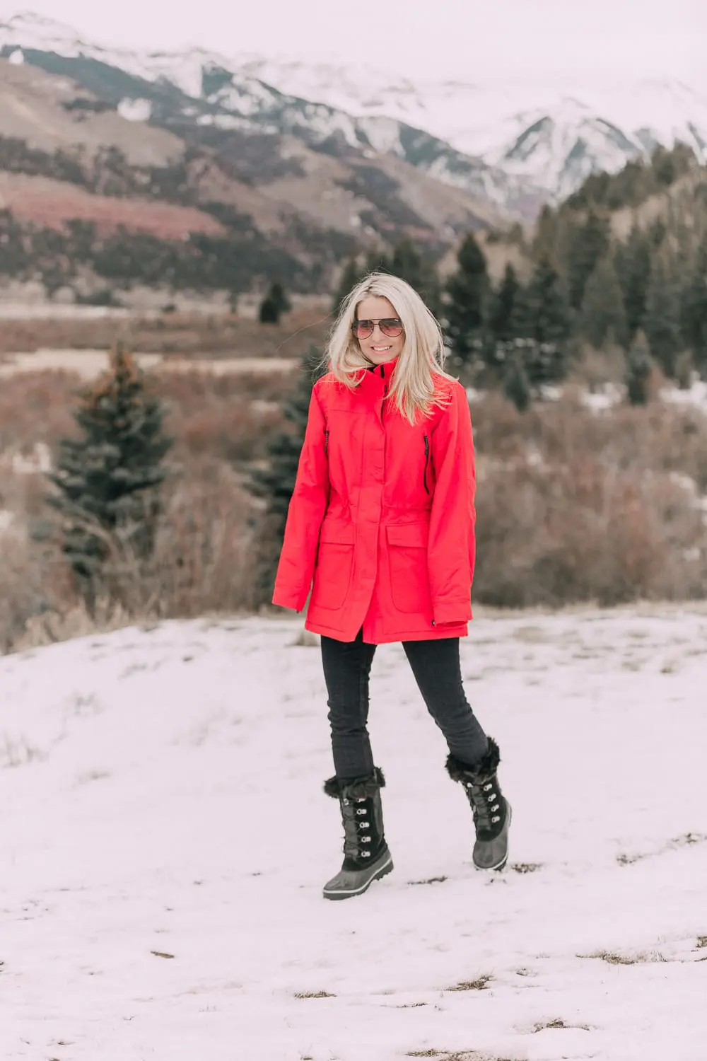 Fashion Blogger Erin Busbee of BusbeeStyle.com wearing a Land's End red parka with Sorel snow boots and some black jeans walking in the snow in Telluride, Colorado