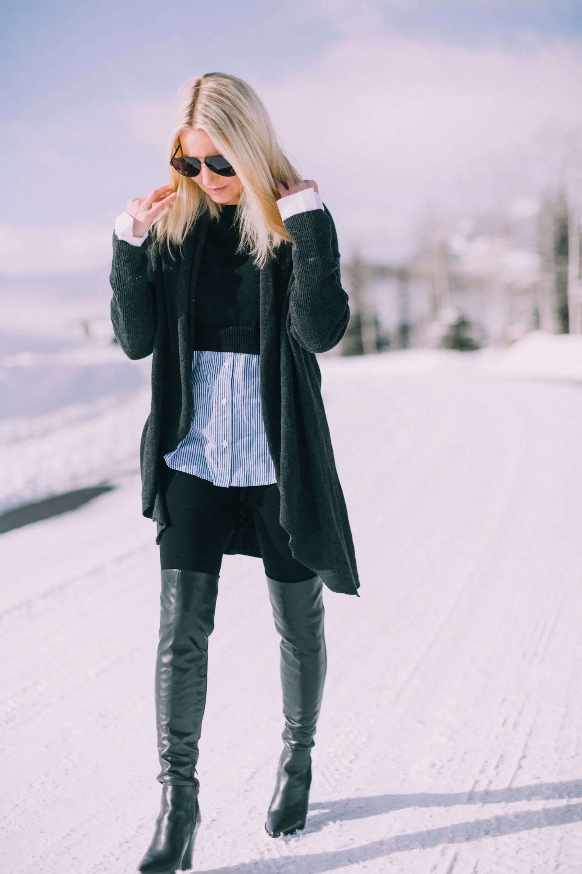 blond fashion blogger over 40 showing how to wear black Spanx leggings in an outfit with Sam Edelman Valda over the knee boots and Barefoot Dreams cardigan in the snow