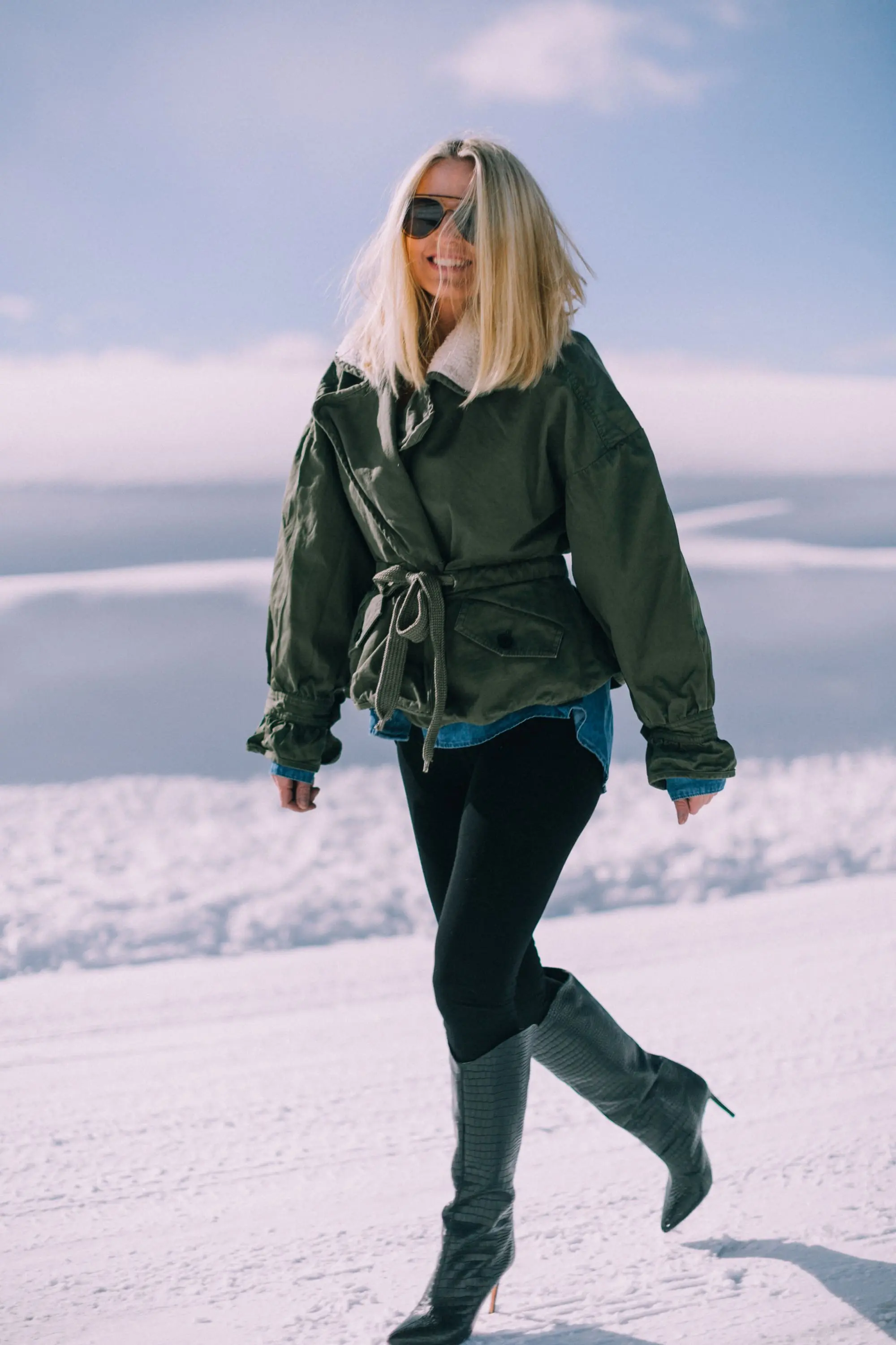 fashion blogger over 50 showing an age-appropriate outfit with black Spanx leggings green Marissa Webb jacket and black Schutz heeled boots