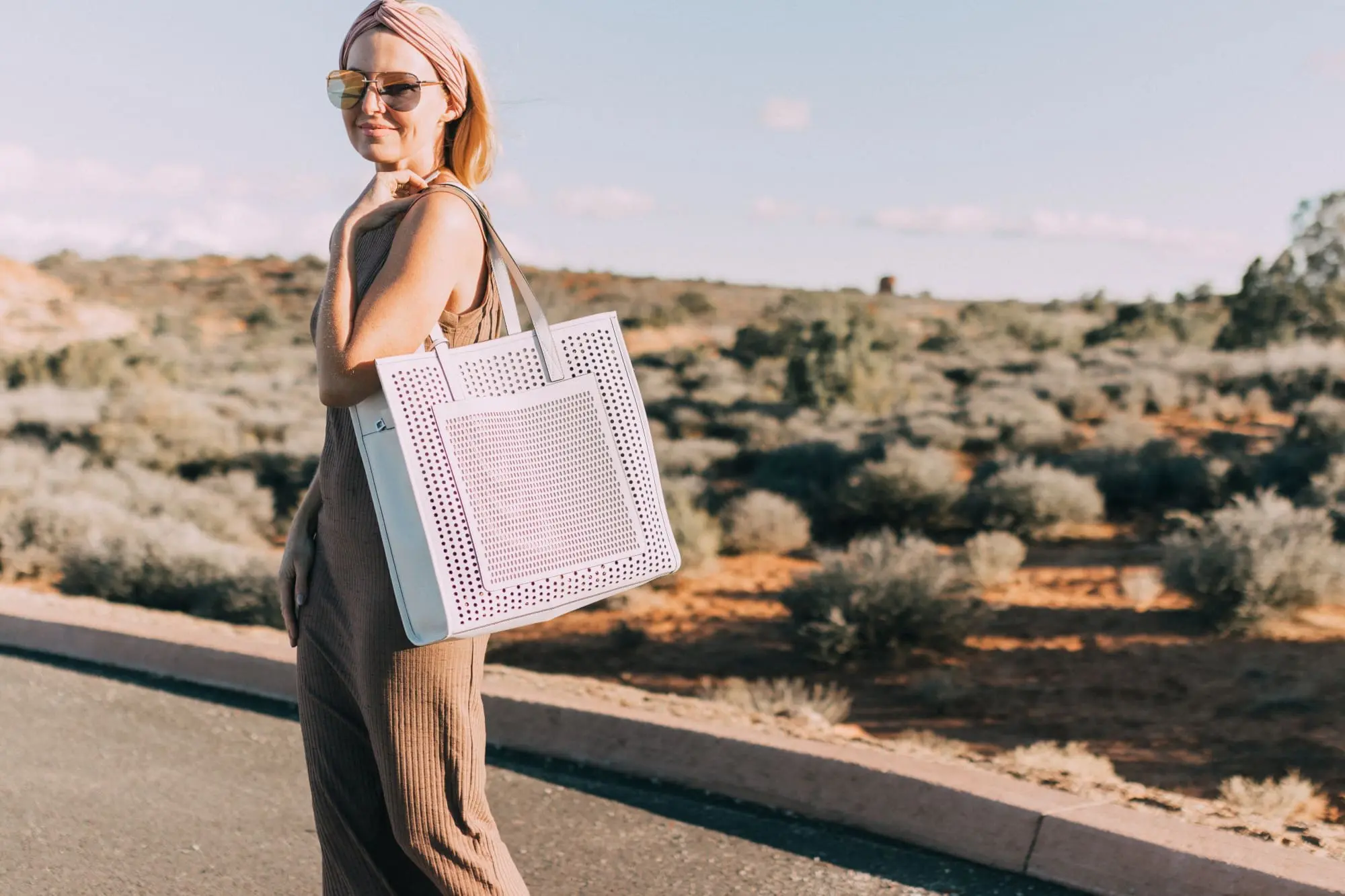 Spring Handbags, Fashion blogger Erin Busbee of BusbeeStyle.com wearing a brown sweater dress by David Lerner from Revolve, a white perforated tote bag fromVince Camuto, and white ankle strap sandals from Vince Camuto in Moab, Utah
