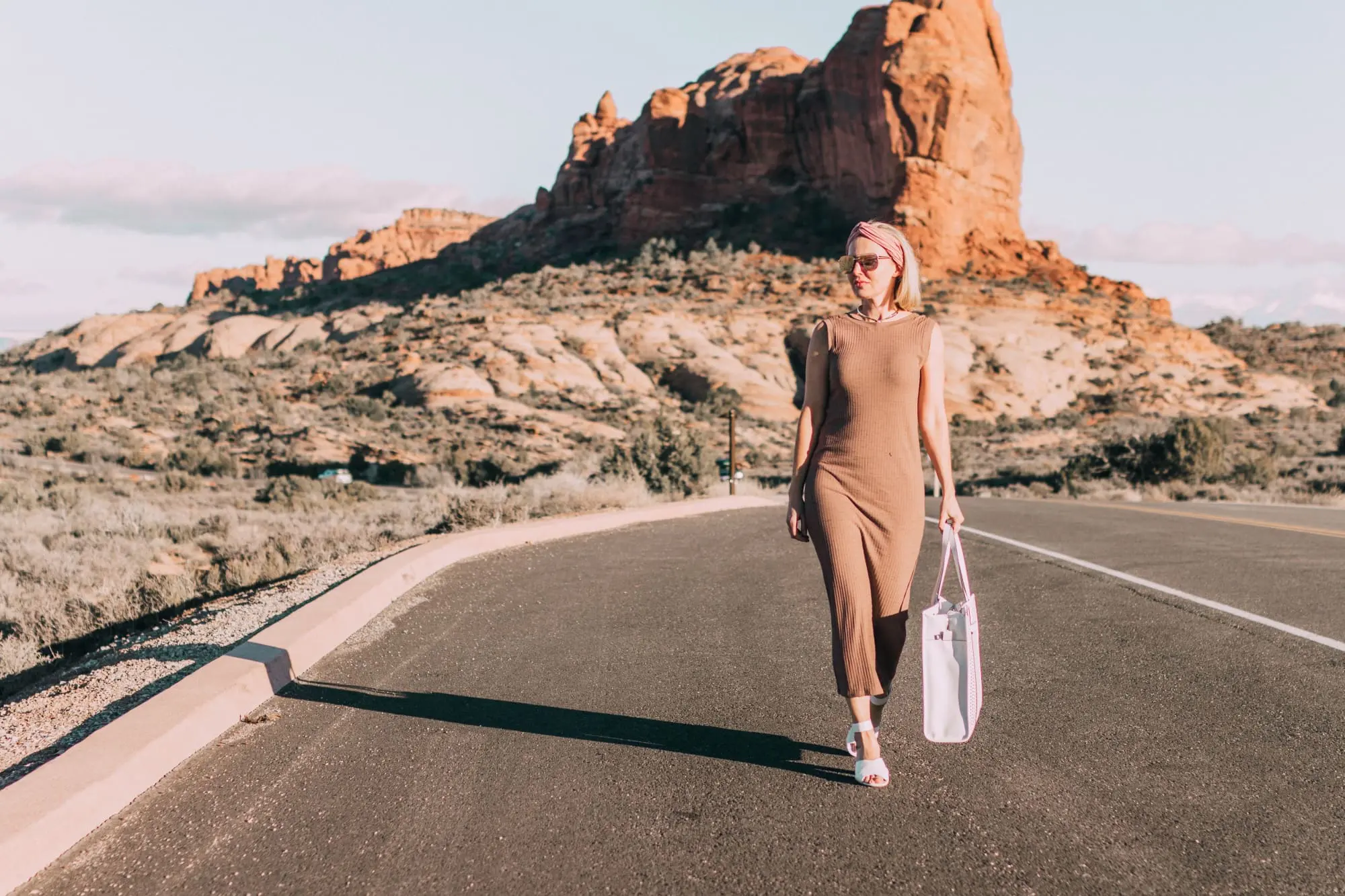Spring Handbags, Fashion blogger Erin Busbee of BusbeeStyle.com wearing a brown sweater dress by David Lerner from Revolve, a white perforated tote bag fromVince Camuto, and white ankle strap sandals from Vince Camuto in Moab, Utah