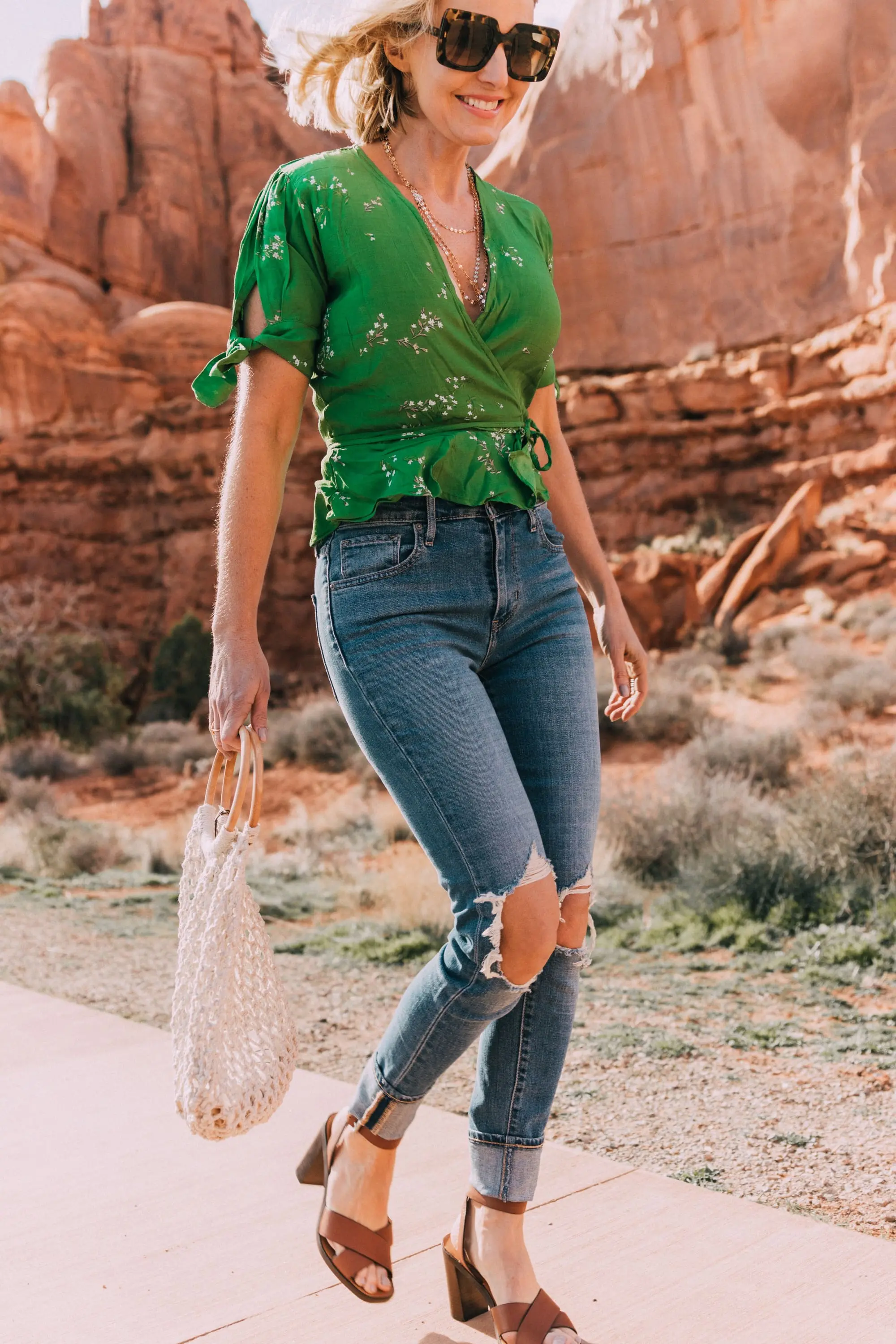 fashion blogger wearing faithfull the brand green lucy wrap top and levi's 721 skinny blue jeans carrying open knit white handbag
