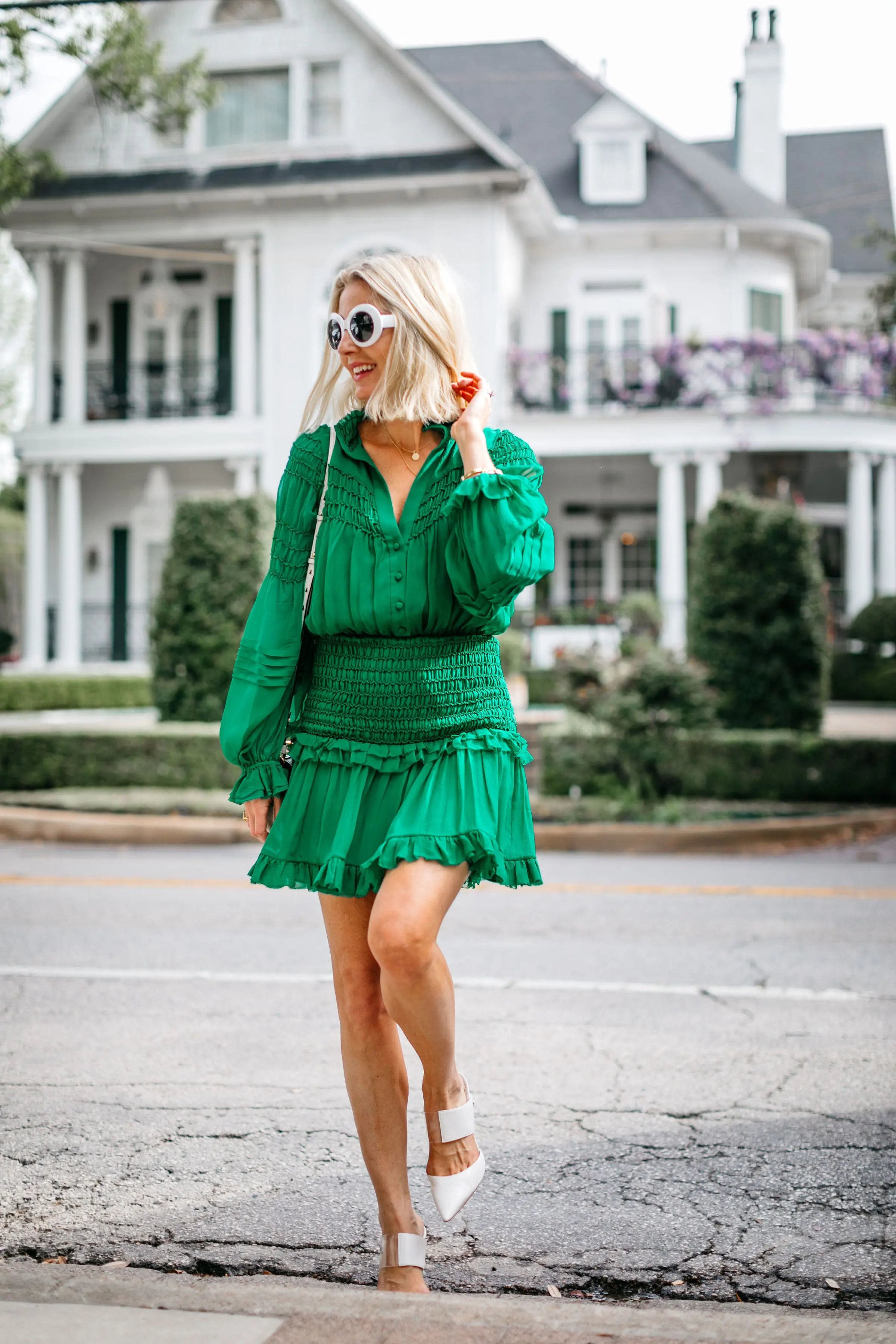fashion blogger wearing green silk mini dress walking across street in white sam edelman heels