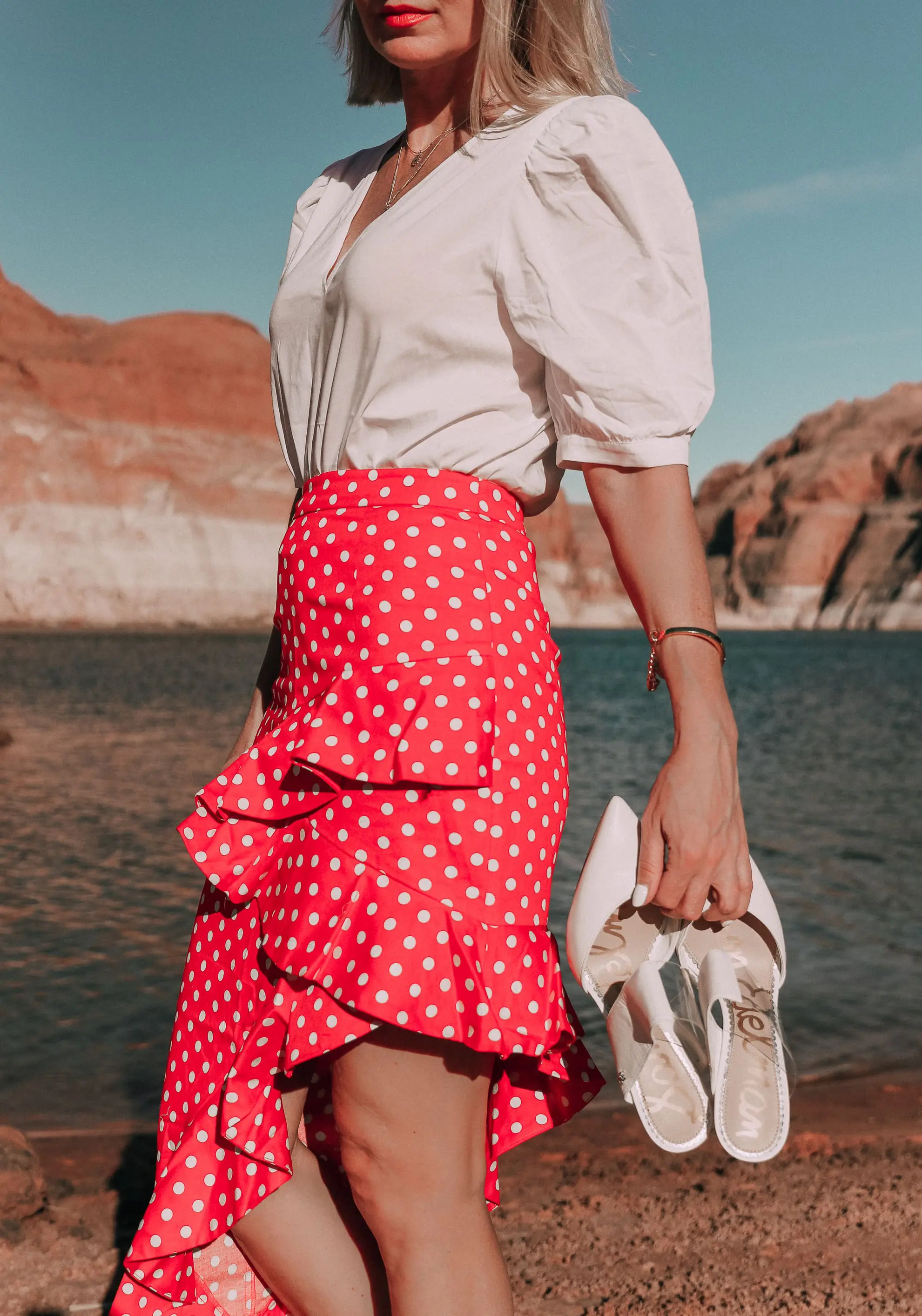 fashion blogger wearing red majorella polka dot ruffle skirt with something navy fitted puff shoulder bodysuit carrying white sam edelman shoes