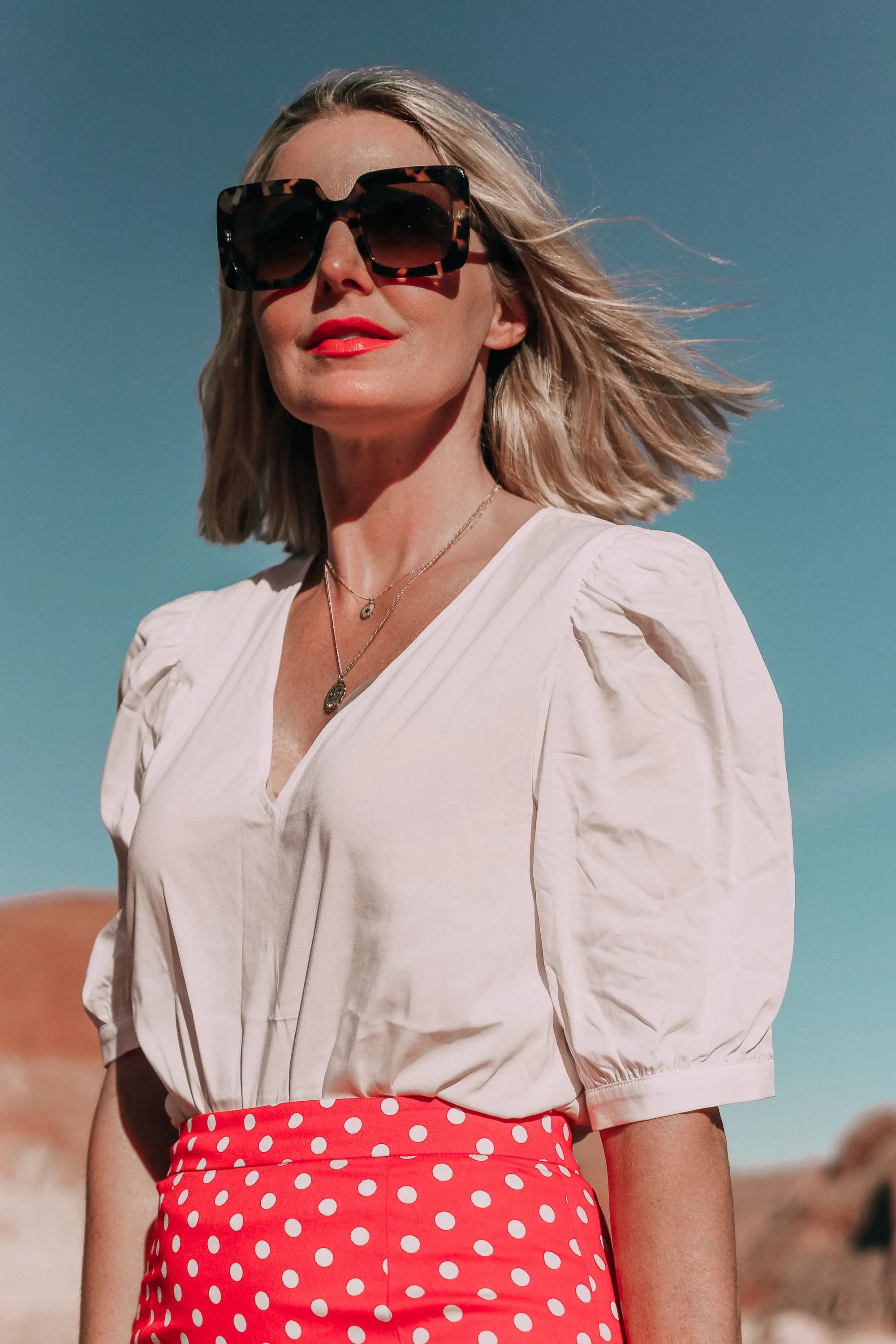 fashion blogger wearing red majorella polka dot ruffle skirt with something navy fitted puff shoulder bodysuit and diff sunglasses