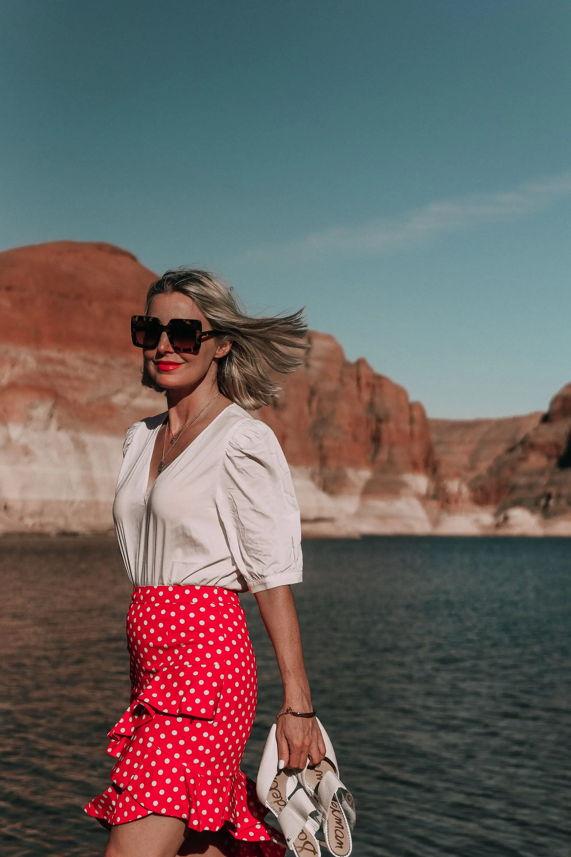 fashion blogger wearing red majorella polka dot ruffle skirt with something navy fitted puff shoulder bodysuit carrying white sam edelman shoes