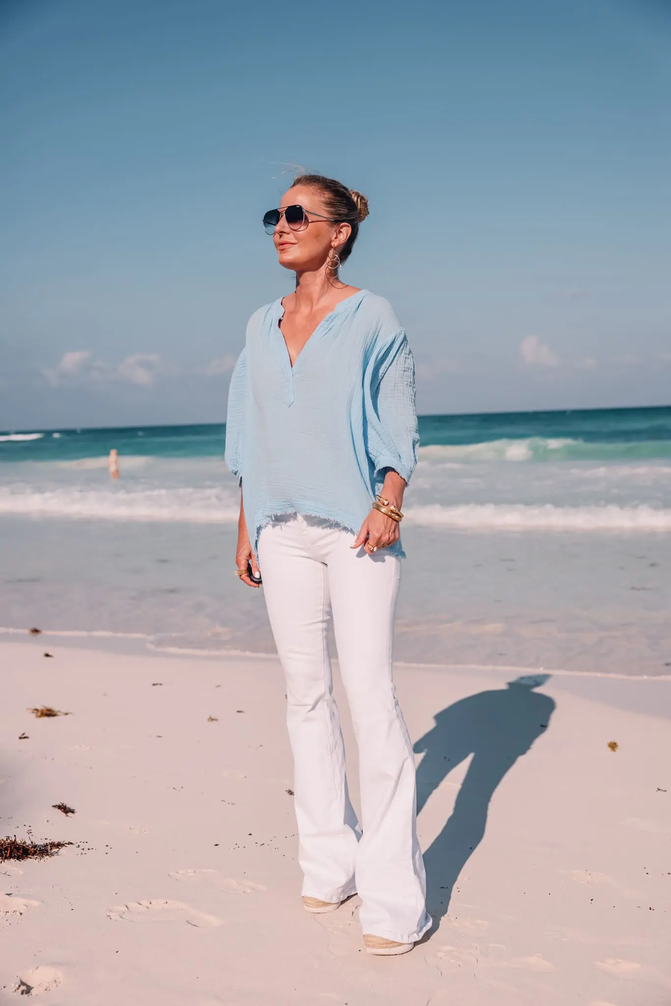 blue cotton gauze 9seed top paired with white jeans on fashion over 40 blogger Erin Busbee at beach
