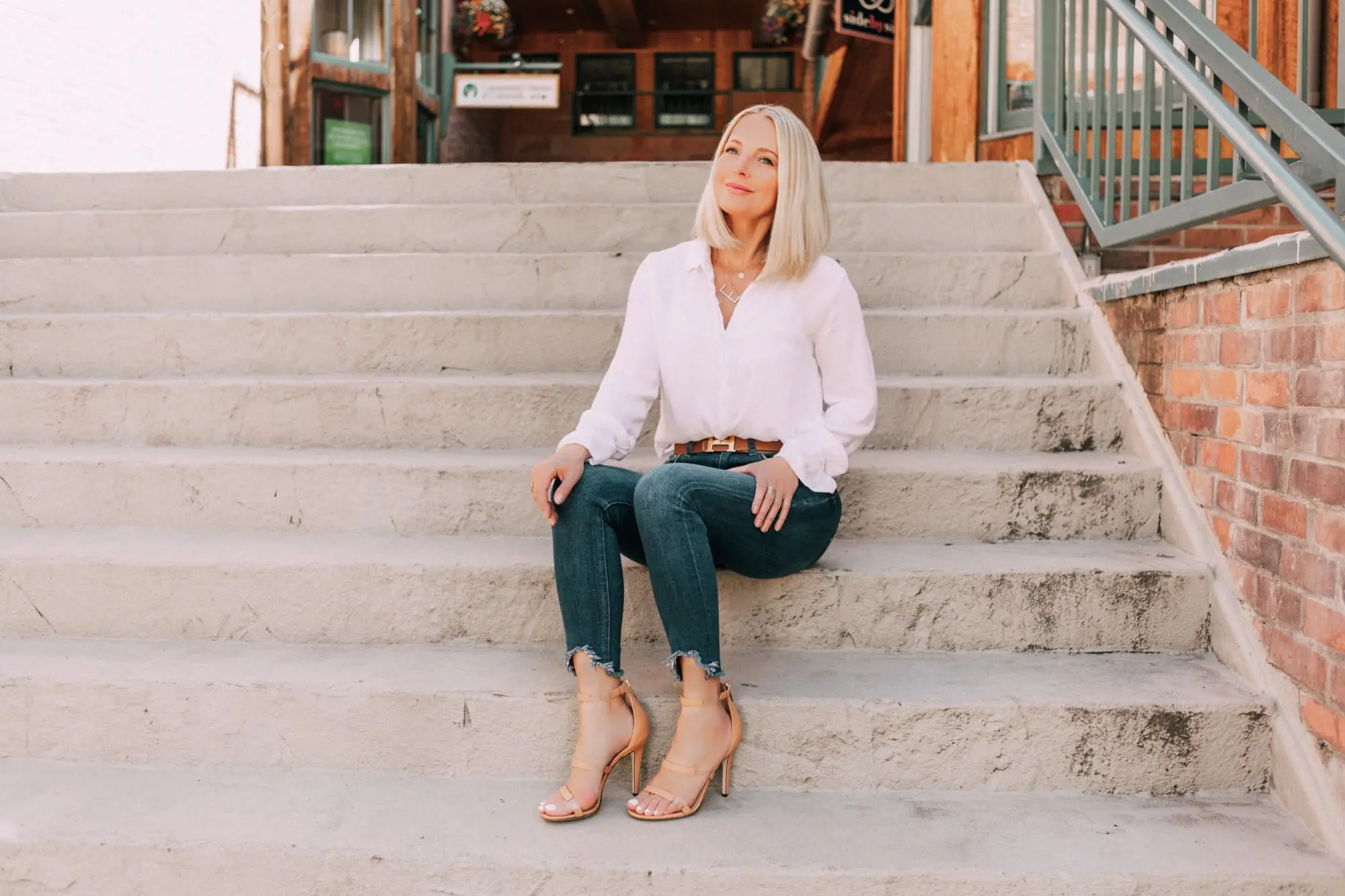 Tamara Mellon, Fashion blogger Erin Busbee of BusbeeStyle.com wearing dark was skinny jeans and white top with stunning Tamara Mellon Frontline heels in Telluride, Colorado