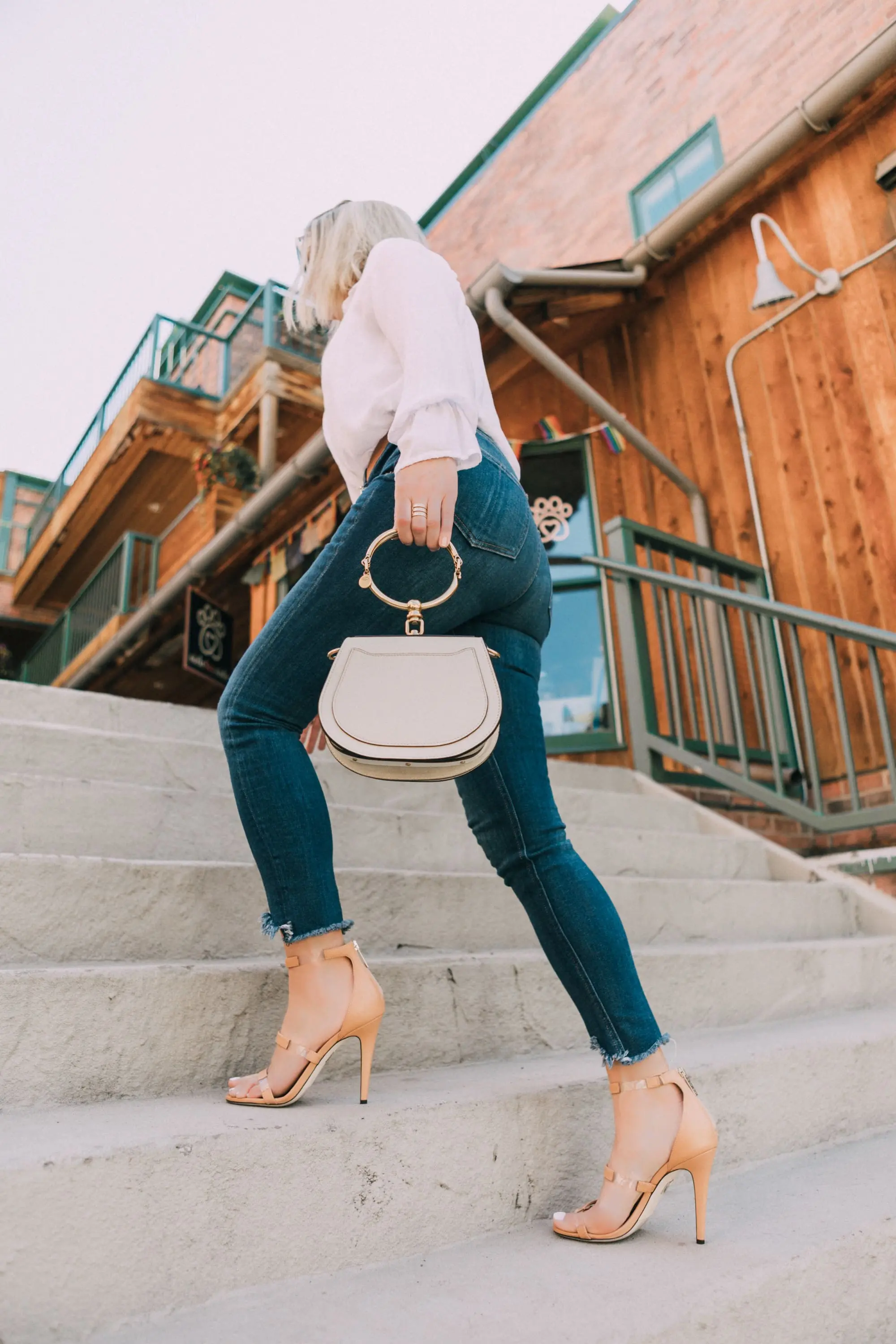 Tamara Mellon, Fashion blogger Erin Busbee of BusbeeStyle.com wearing dark was skinny jeans and white top with stunning Tamara Mellon Frontline heels in Telluride, Colorado