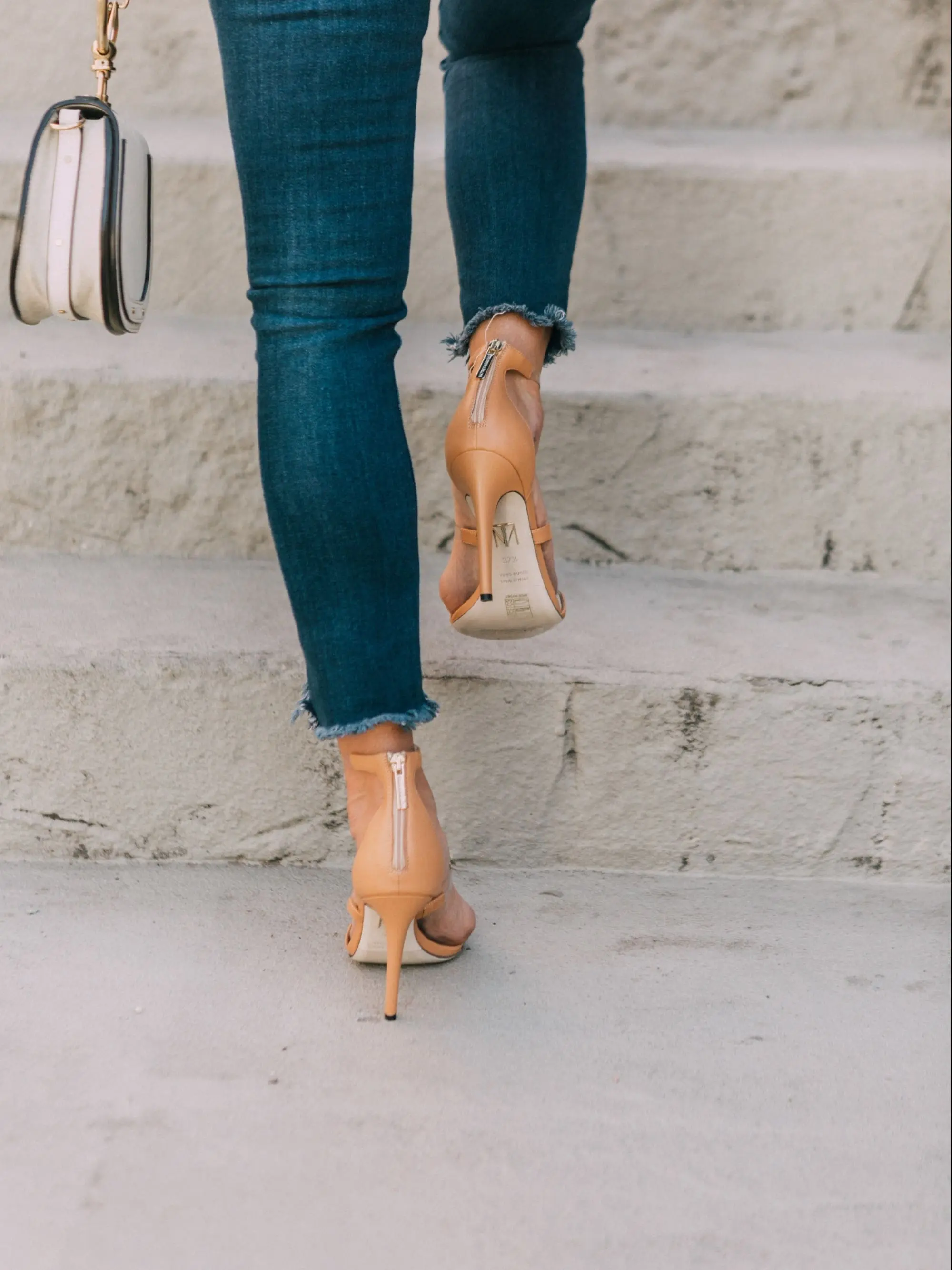 Tamara Mellon, Fashion blogger Erin Busbee of BusbeeStyle.com wearing dark was skinny jeans and white top with stunning Tamara Mellon Frontline heels in Telluride, Colorado