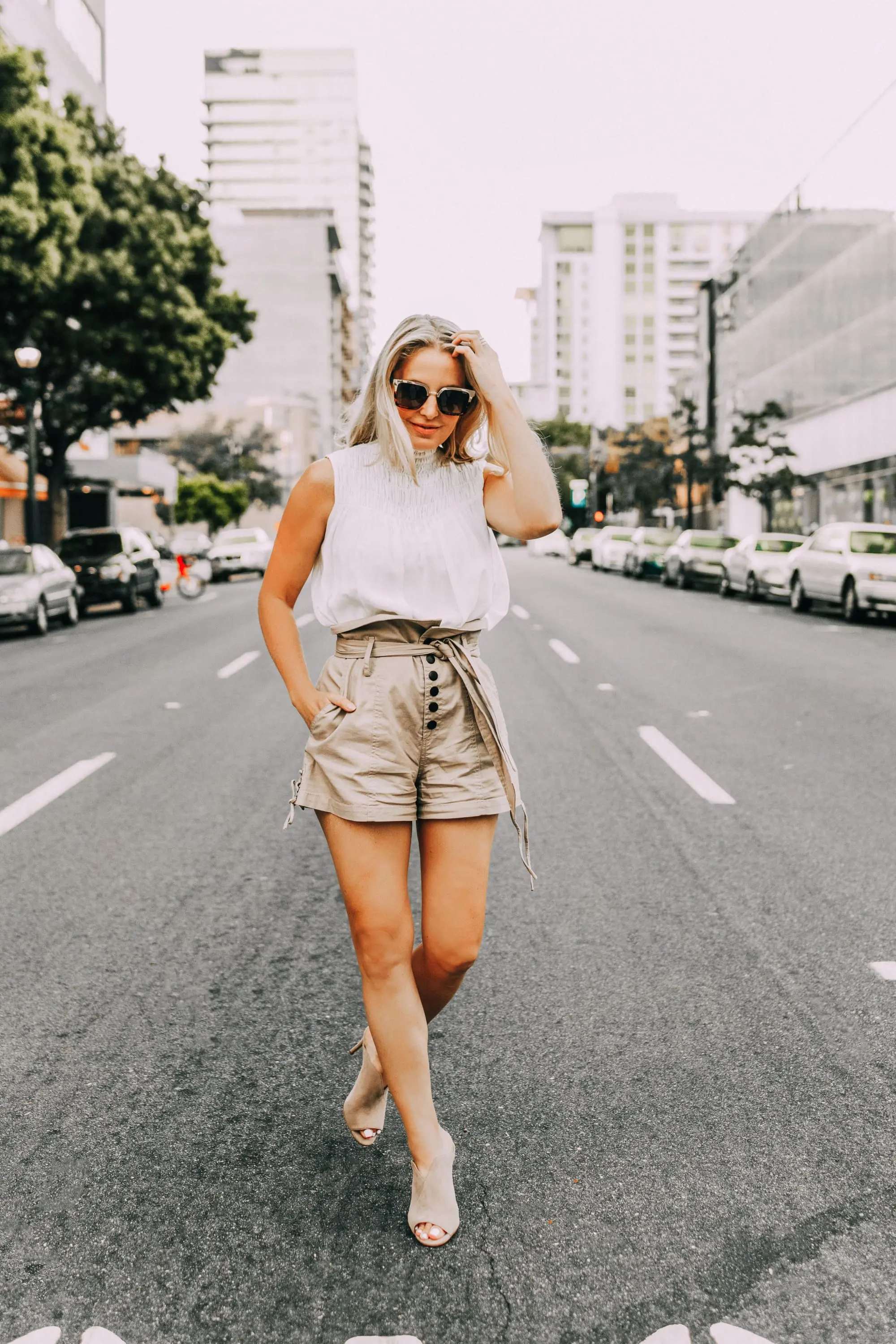 fashion blogger erin busbee wearing khaki paper bag shorts with white sleeveless high neck top peep toe mules in san diego 