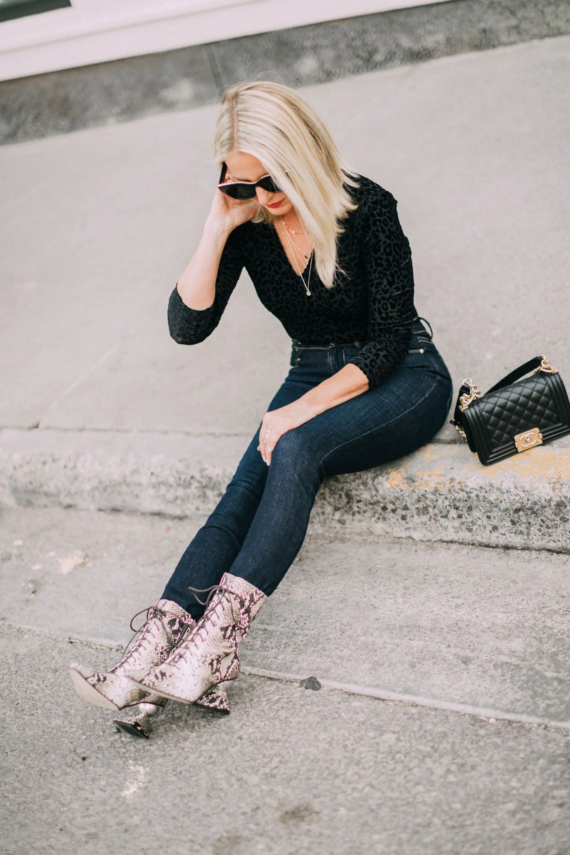Yuul Yie, Fashion blogger Erin Busbee of BusbeeStyle.com wearing dark wash skinny jeans by L'Agence, leopard print bodysuit by ASTR the label, black Chanel boy bag, and Yuul Yie python boots in Telluride, CO