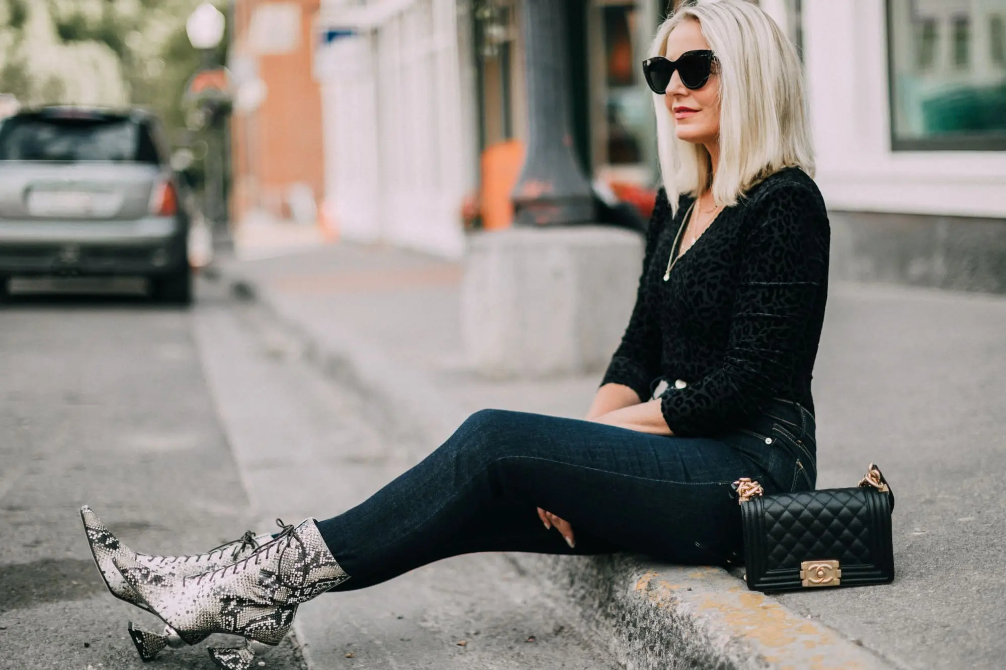Yuul Yie, Fashion blogger Erin Busbee of BusbeeStyle.com wearing dark wash skinny jeans by L'Agence, leopard print bodysuit by ASTR the label, black Chanel boy bag, and Yuul Yie python boots in Telluride, CO