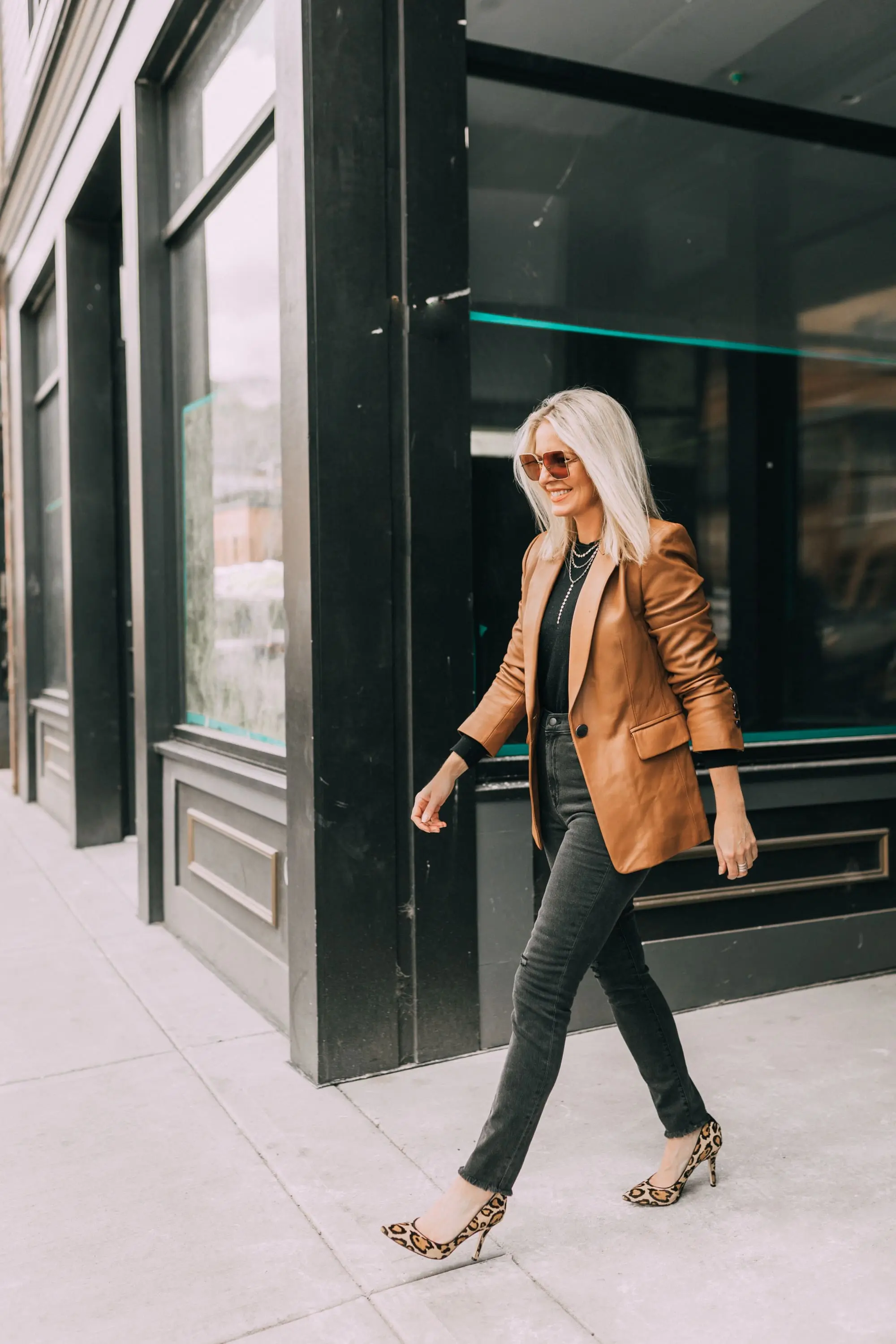 Brown and black outfit, fashion blogger Erin Busbee of BusbeeStyle.com wearing a brown leather blazer by Kobi Halperin, black distressed jeans by J Brand, black puff sleeve cashmere sweater by AQUA, gold Baublebar layered necklace, and leopard print Sam Edelman pumps in Telluride, Colorado