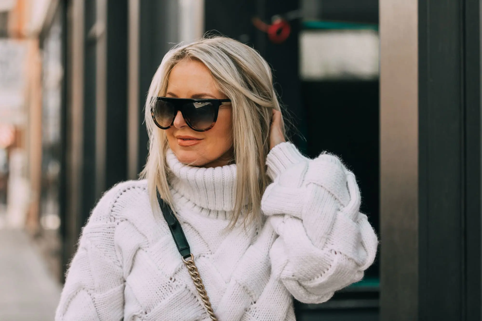 fashion blogger showing how to style dad sneakers in outfit with white chunky sweater for fall chanel handbag