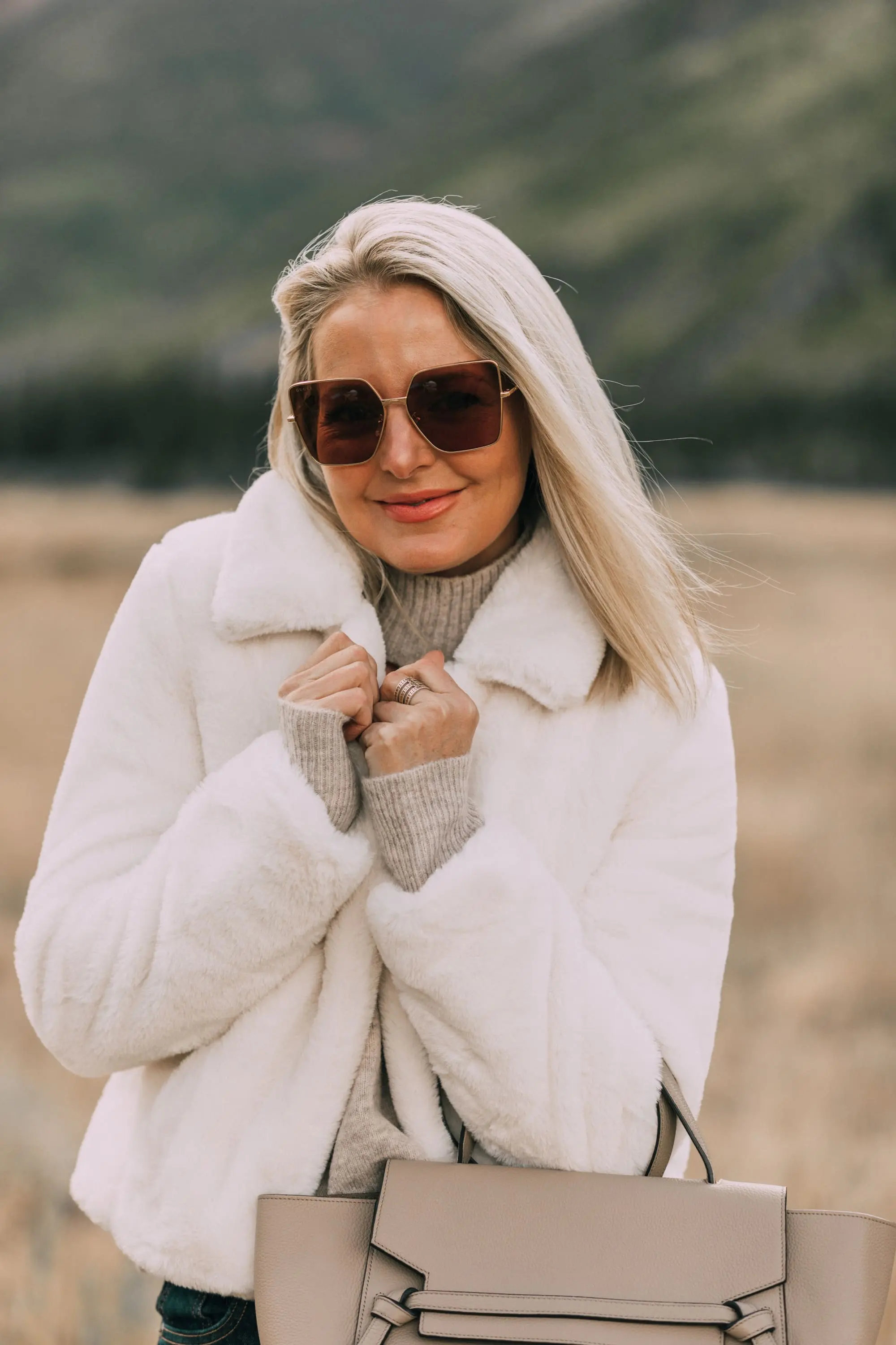 Fuzzy Jackets, Fashion blogger Erin Busbee of BusbeeStyle.com wearing a cream Blank NYC faux fur jacket with a choker sweater and jeans in Telluride, CO